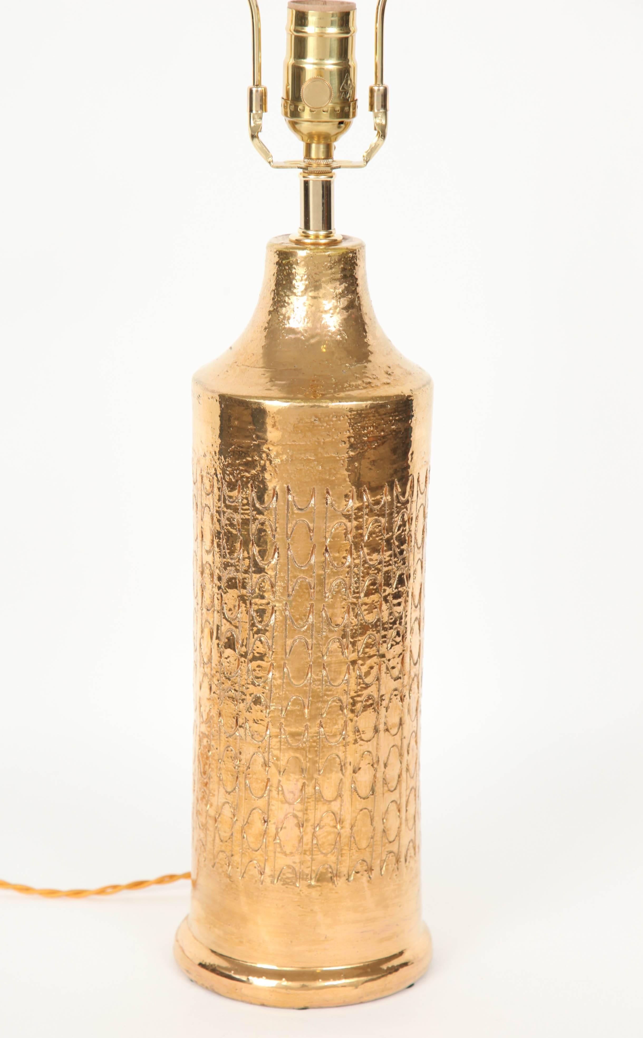 Fantastic pair of modern bottle form lamps with an overall incised pattern and a gold glaze by Bitossi for Bergboms. Lamps have been rewired for use in the USA with brass hardware and twisted silk cord. Ceramic body measures 18.5