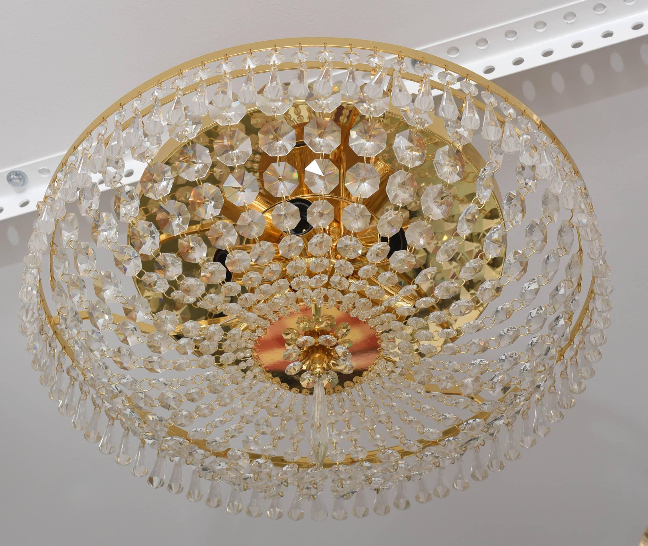 This glamorous Hollywood-Regency style chandelier was made by the firm of Dolzauer of Austria in the 1960s. It has Swarovski crystals and gold-plated trim. 

Note: This piece requires six Edison based bulbs.

Please feel free to contact us for