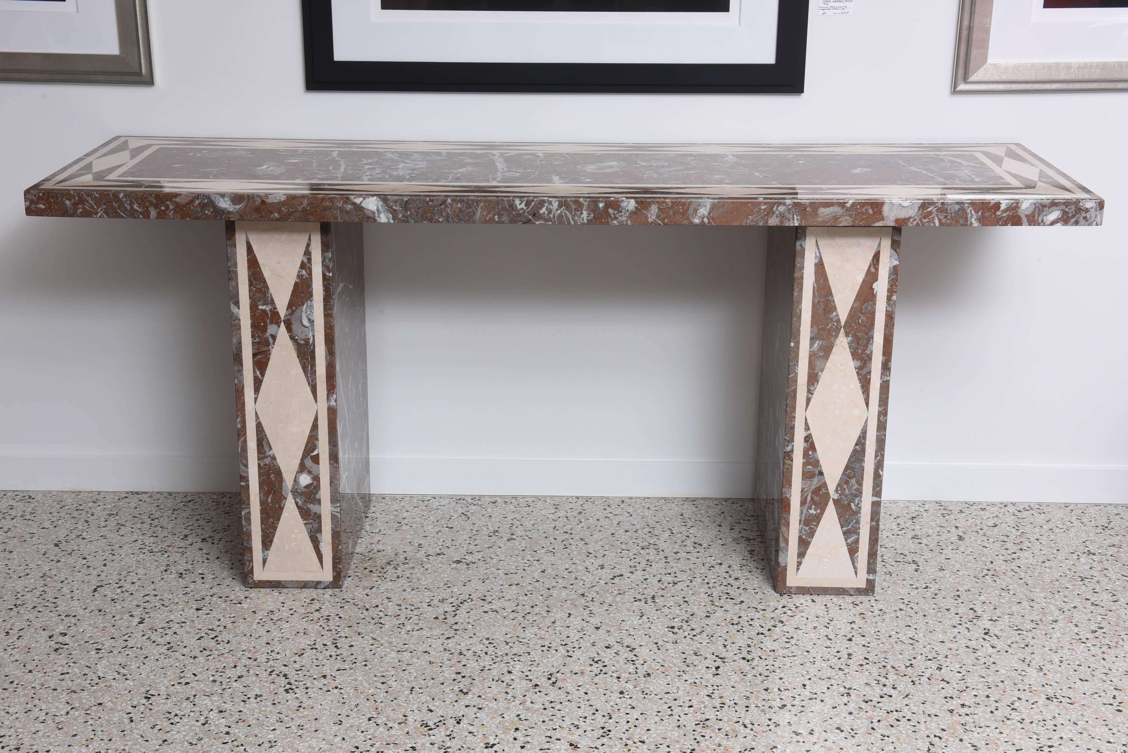 The main body of this console table is composed of red-variegated marble with inset ivory marble. The top is inset with a double-lined border with a diamond pattern as are the front of the legs. 

