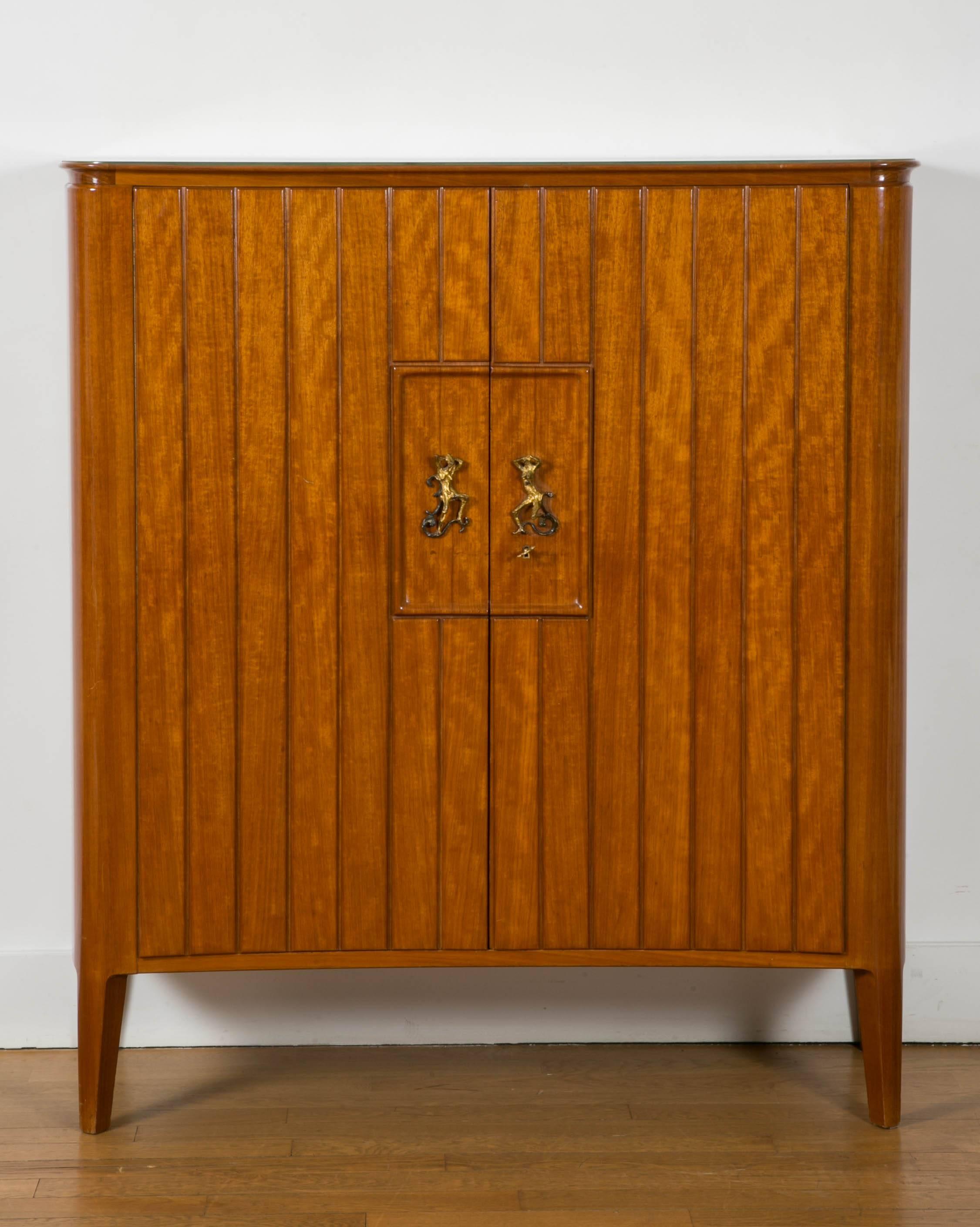 Elegant mahogany cabinet, 1945-1950, by Osvaldo Borsani, Italy.
With central gilt bronze ornament by Lucio Fontana.
Gold leaf glass top. Sycamore inside with drawers and shelves.
Label. 
Original lightly curved piece, with sculpted handles.