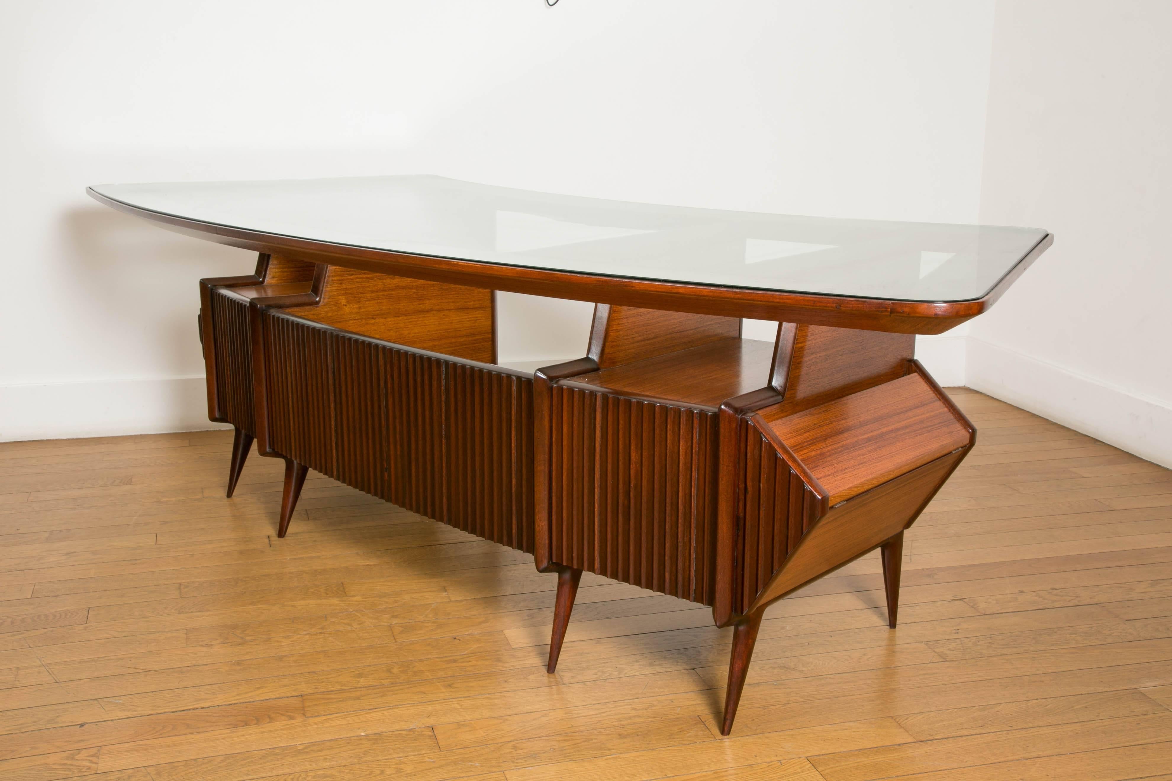 Large elegant desk. by Carlo di Carli, 1950, Italy.
Rosewood and mahogany base, with a bowed framed glass top, 
central glass tablet, four drawers and original side cases. On eight feet.
Inside top length: 180 cm.
 