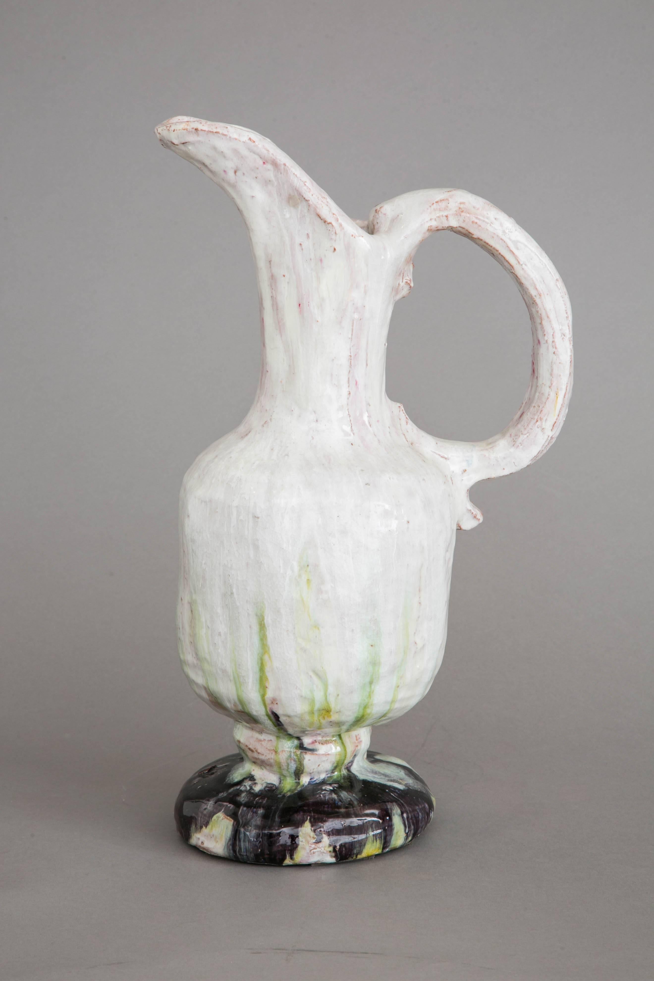 Elegant enameled stoneware ewer vase, with a large handle, 1950s, by Alice Colonieu (1924-2010).
Milky white and pink dropping enamel with green highlights, on a dark base.
Signed. 

Alice Colonieu (1924–2010) was a very original artist, working