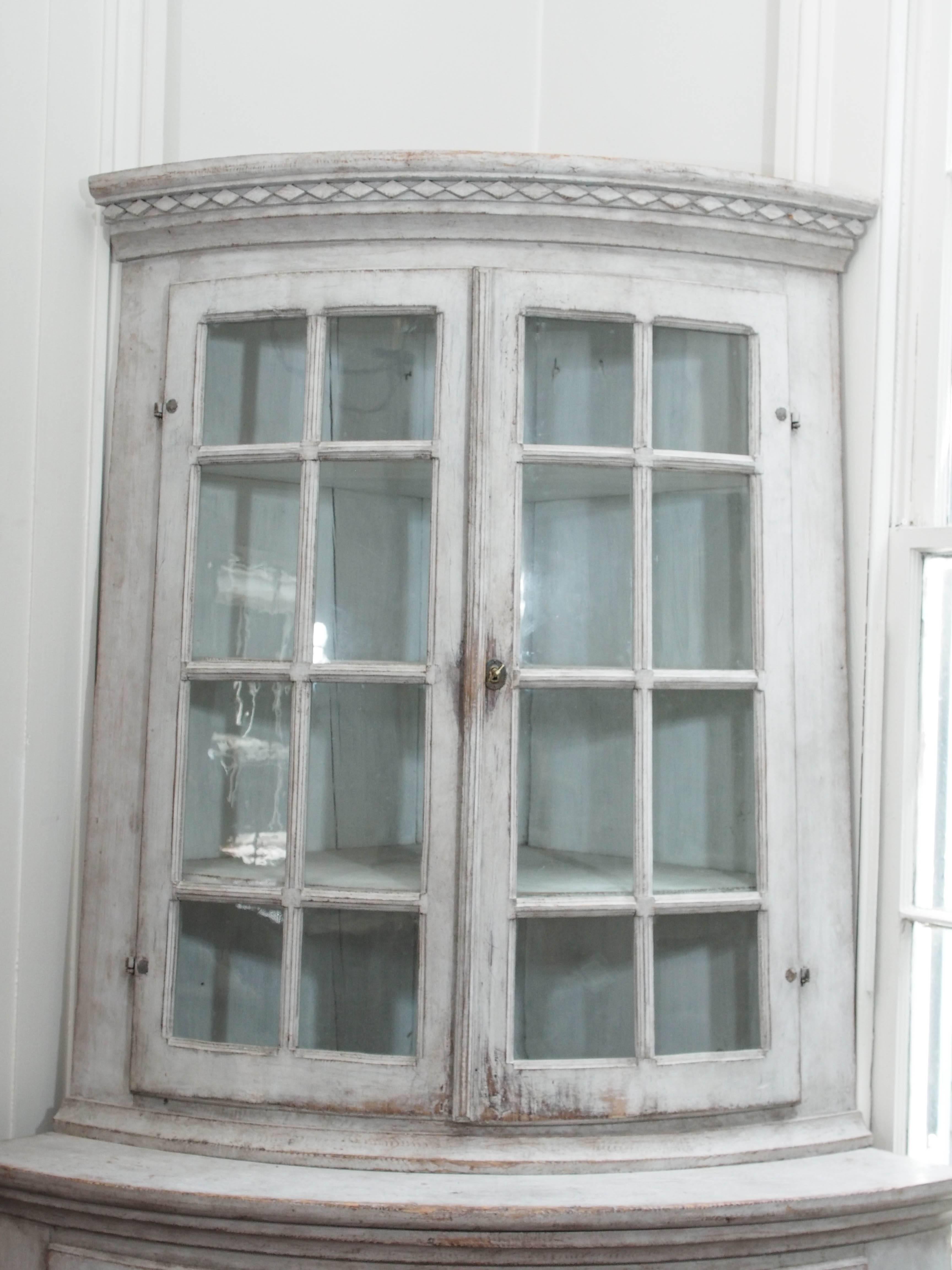19th Century Gustavian style corner cabinet with glass doors on top and fluted doors on the bottom. Painted in a white /pale gray color. Glass is not original.
3 shelves on top and 2 on the bottom.