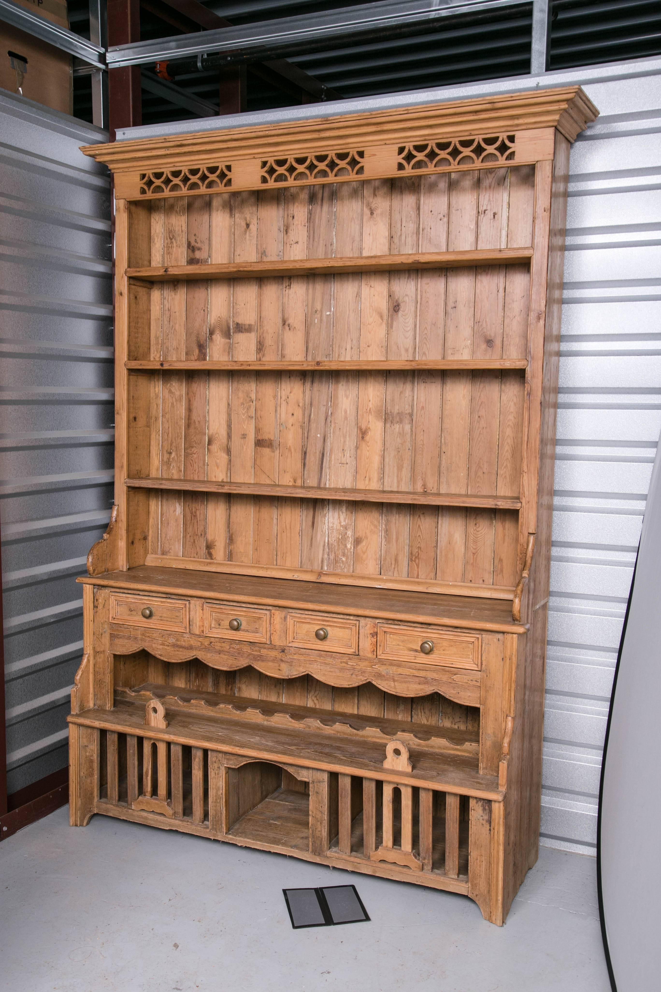 A 19th English solid pine cupboard with elements added over time, two-piece step-back form having four open shelves, over four flush drawers, the open area beneath the drawers fitted with a horizontal wine rack above two chicken coops.