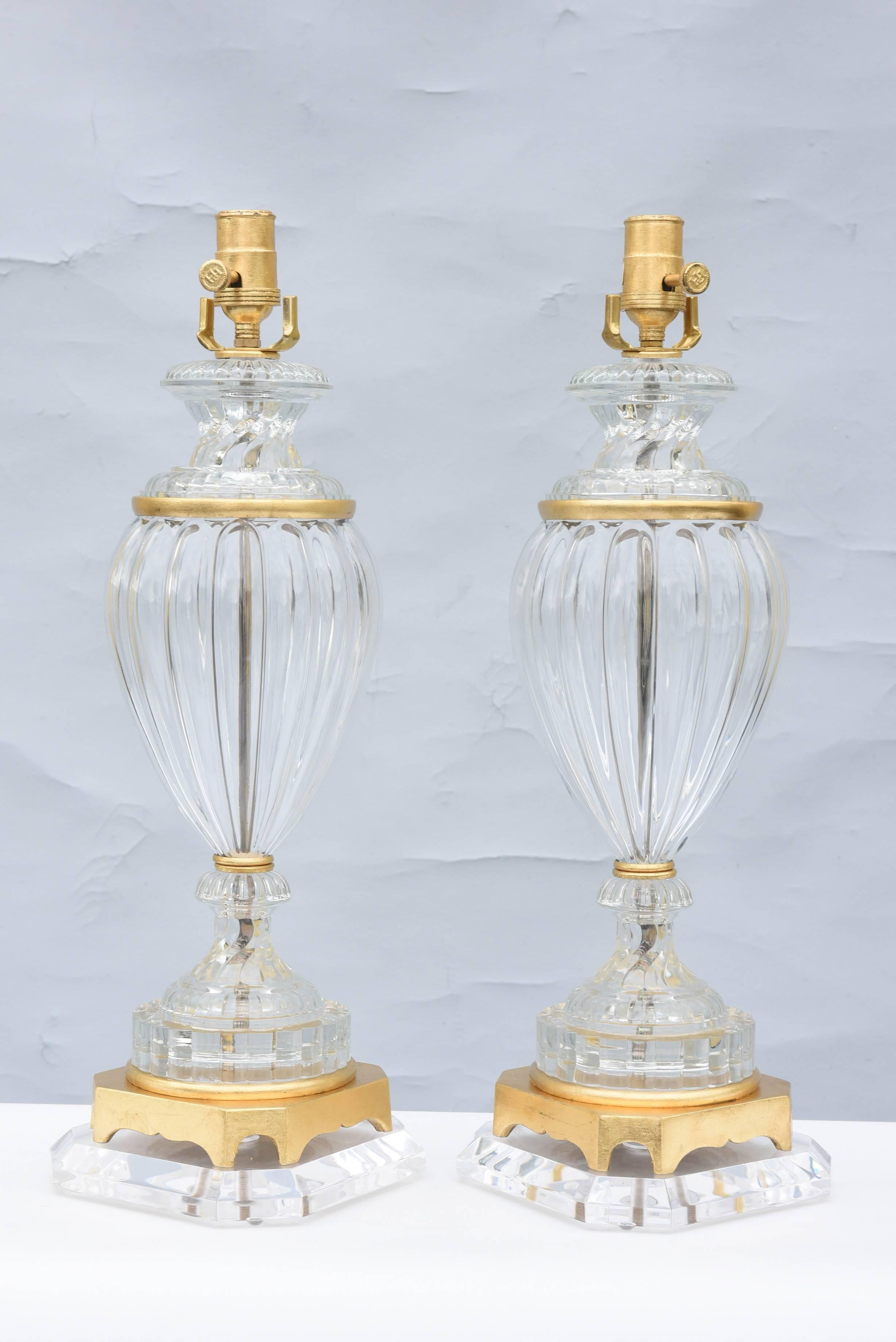 Pair of Paul Hansen Baccarat lamps, of glass, with gilt metal collars, each a reeded, baluster-form urn, on graduated round foot, with gilded base, on a Lucite plinth. 

Stock ID: D6461