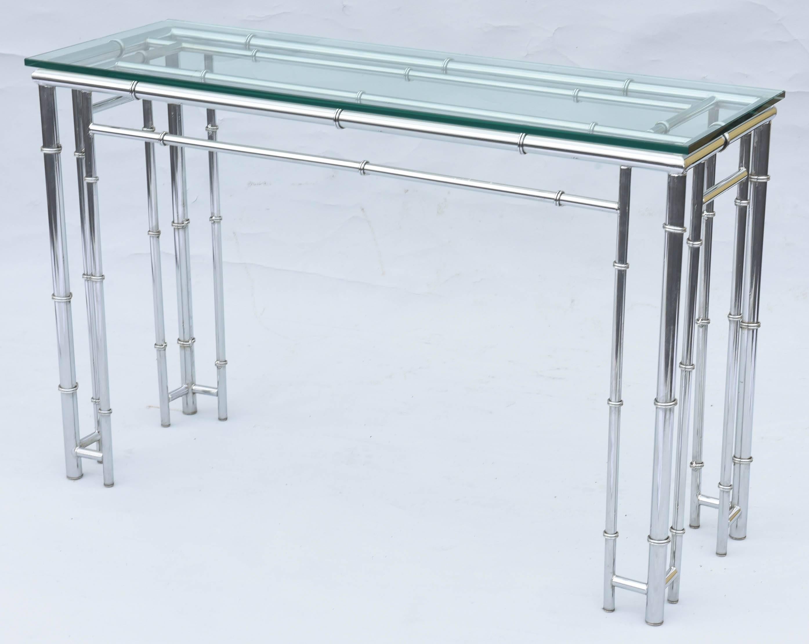 Console table or sofa table, of chrome, having a rectangular top of glass, on faux bamboo base, comprised of joined stretchers, raised on four, triple-column legs. 

Stock ID: D9393