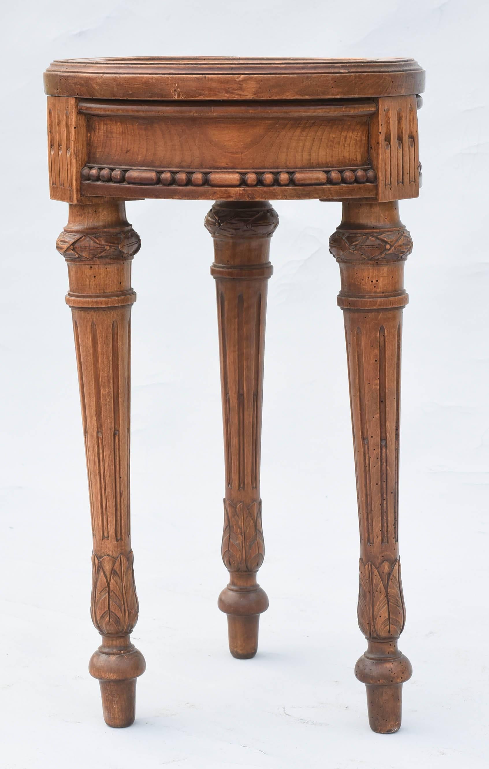 Accent table, of walnut, having a round molded top, inset with marble, its apron carved with rosettes, beads and bars; raised on three round, fluted, tapering legs, with acanthine knees, ending in toupie feet.

Stock ID: D3674