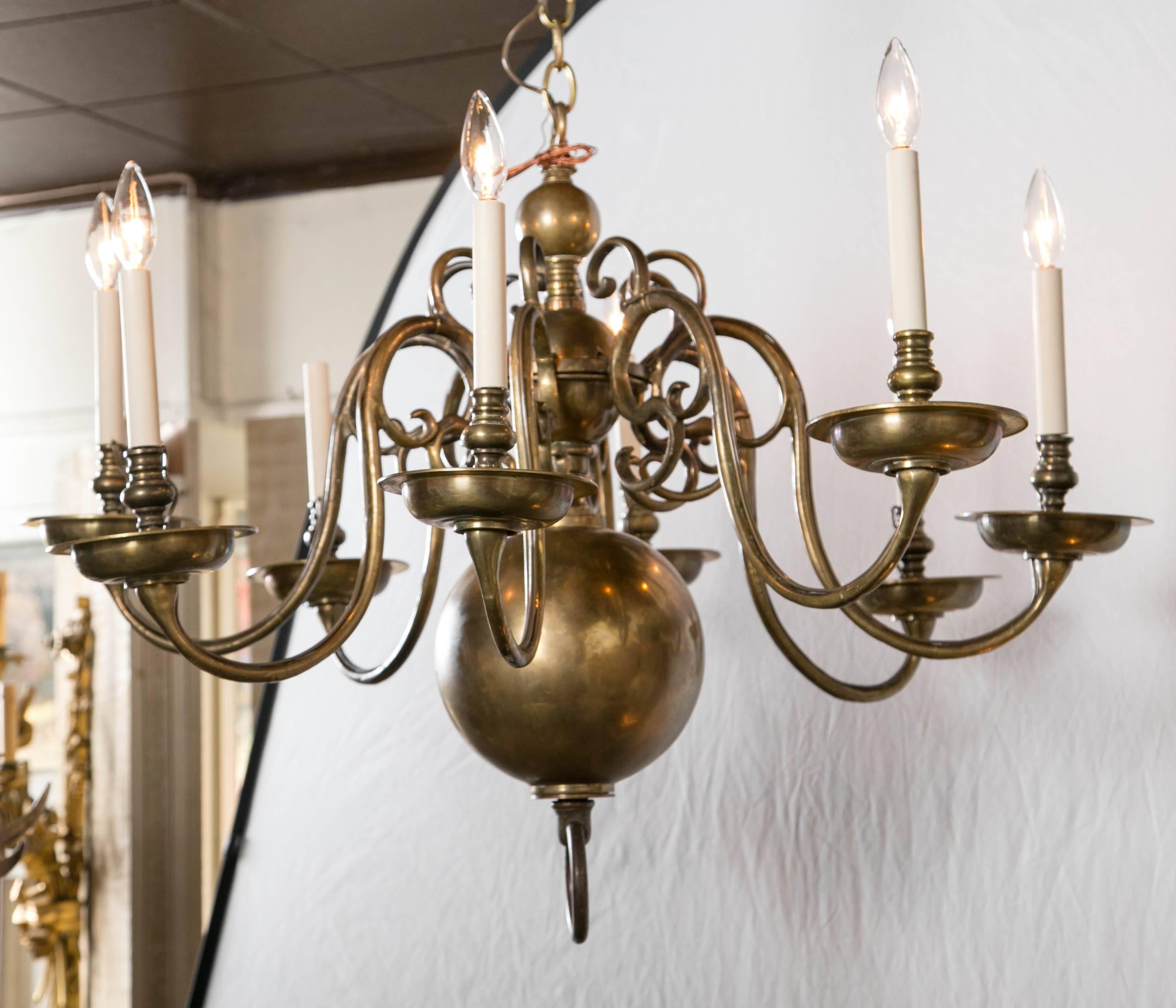 This single tier Dutch or English eight-light brass chandelier dates from the early part of the 19th century. It is electrified and in working order. Graduated brass balls form the central shaft with ring finials at top and bottom. Chandeliers as