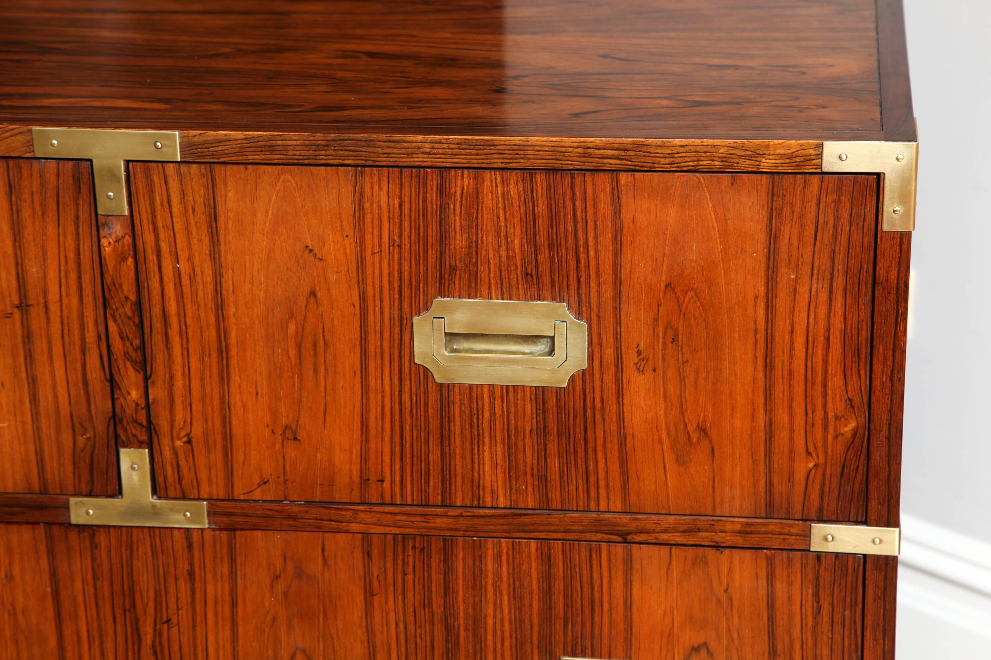 A Rosewood Veneered Anglo-Indian style campaign chests with recessed brass pulls and brass bound edges. The secondary wood and drawers fabricated with hardwoods. The drawer interior bearing label of American maker Baker. Circa 1960. 