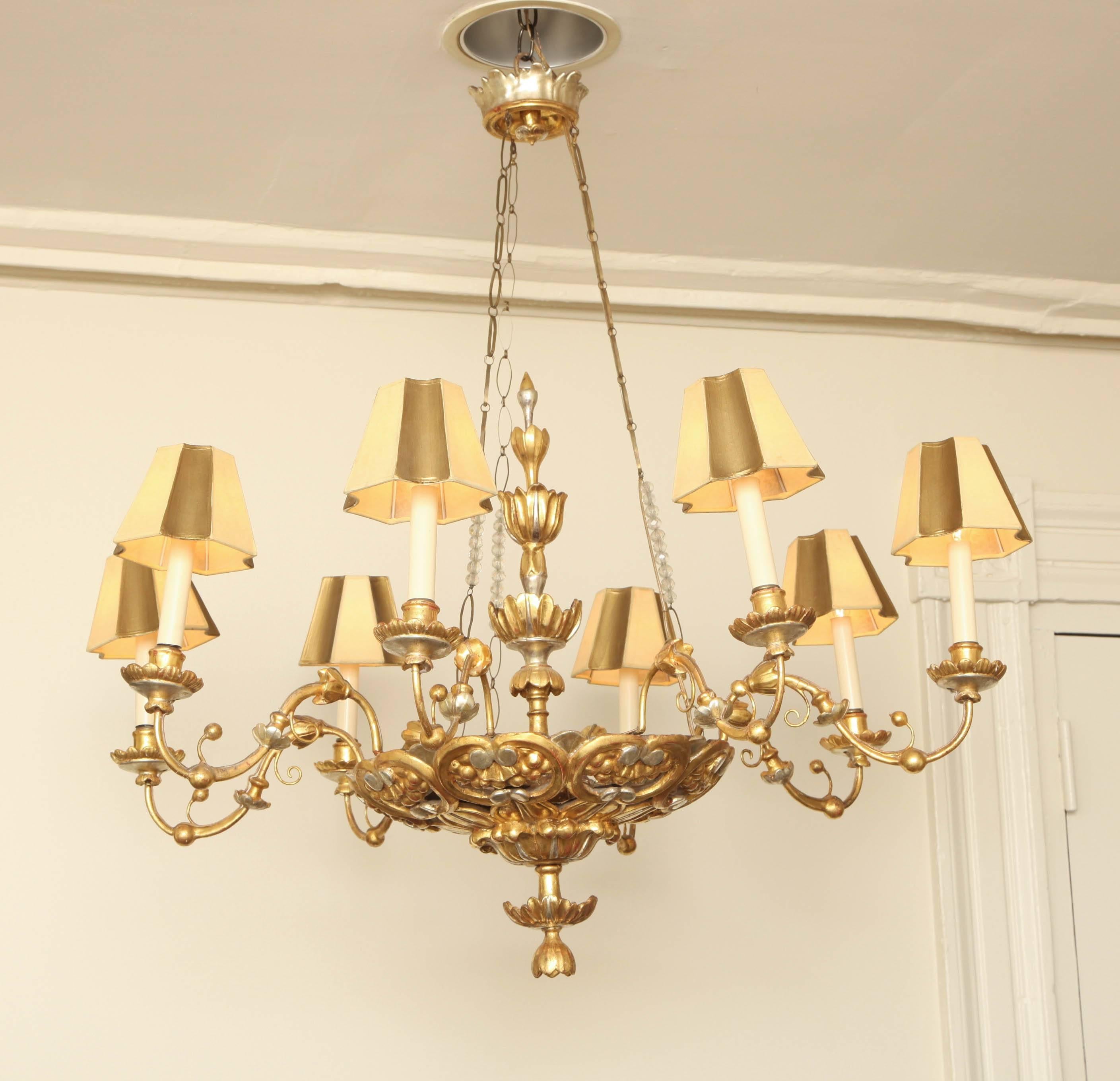 Carved silvered and giltwood chandelier with handmade gilt-metal chains interspersed with 19th century crystal beads. The pierced basket with a foliate knob finial and carved with stylized grape clusters. Wired for electricity.

Provenance: Bernd