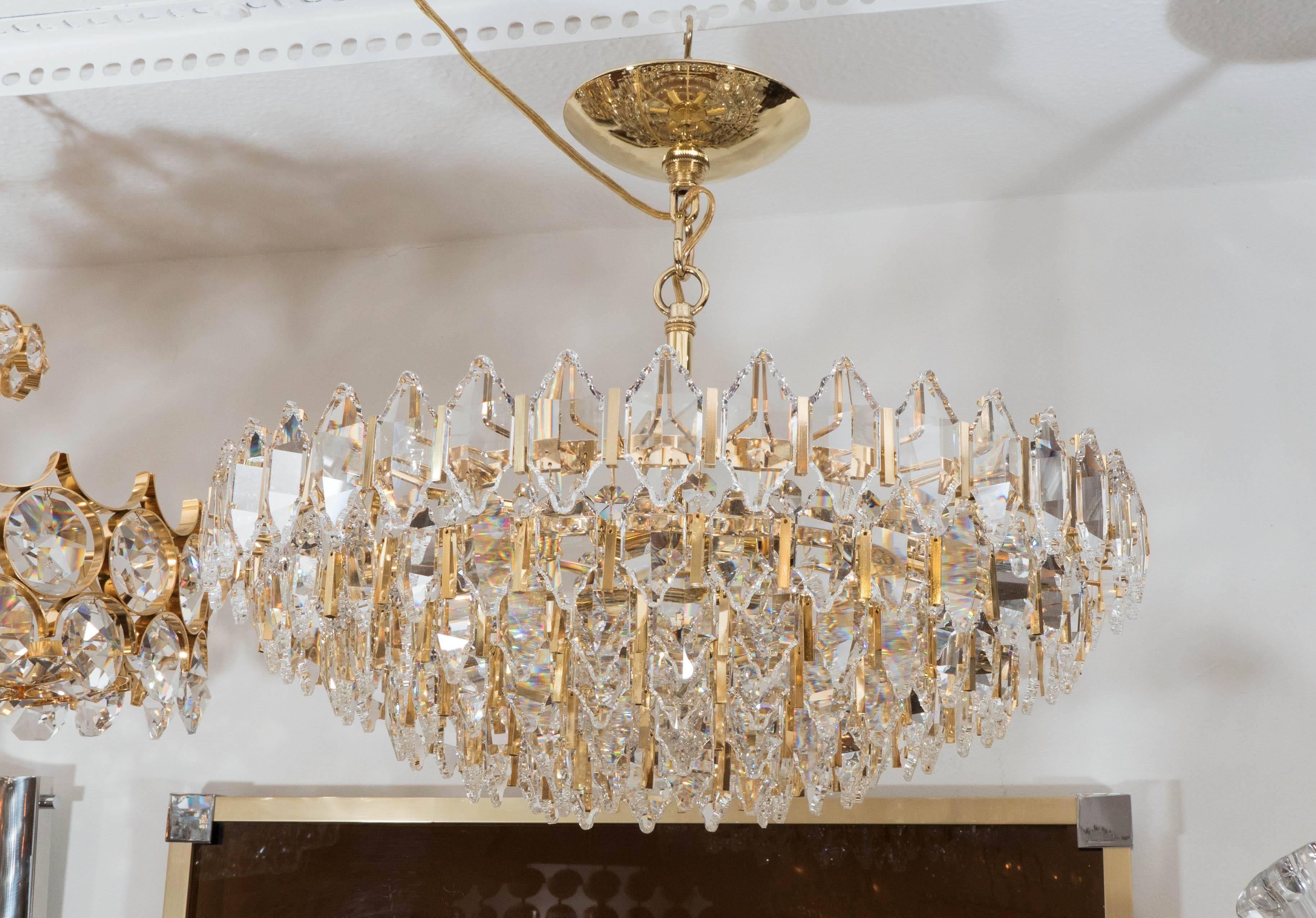Tiered brass chandelier featuring suspended diamond-shaped, facet-cut crystal elements.