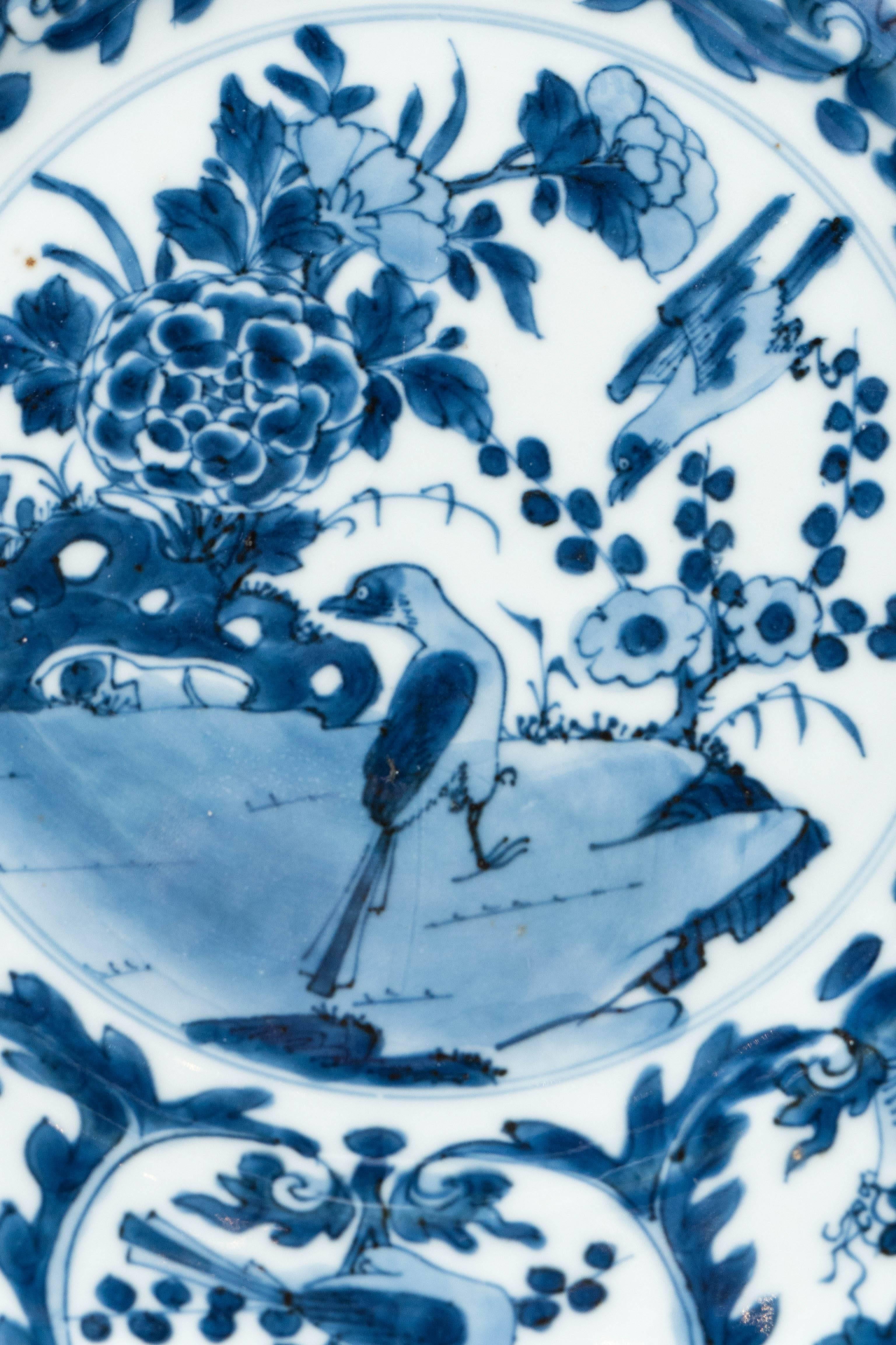 A set of 18th century Chinese Blue and White dishes made during the reign of the Qianlong Emperor (1736-1795). The dishes are hand-painted in a deep cobalt blue. The center scene is shows a pair of songbirds in a garden filled with peonies and a