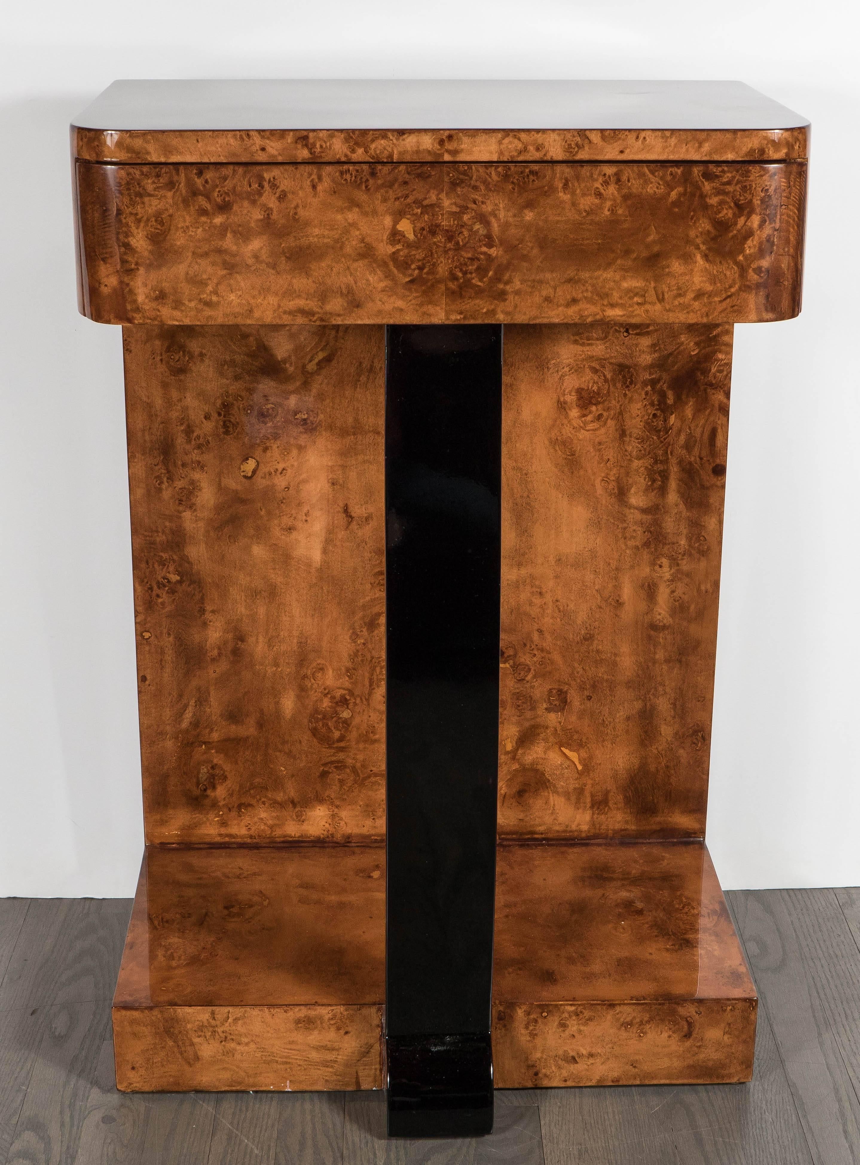 This piece features a generous pull-out drawer and bowed-front, black-lacquered center support and exotic bookmatched burled elm detailing all around. Streamlined design with machine age inspiration. This sized piece would lend well alongside a