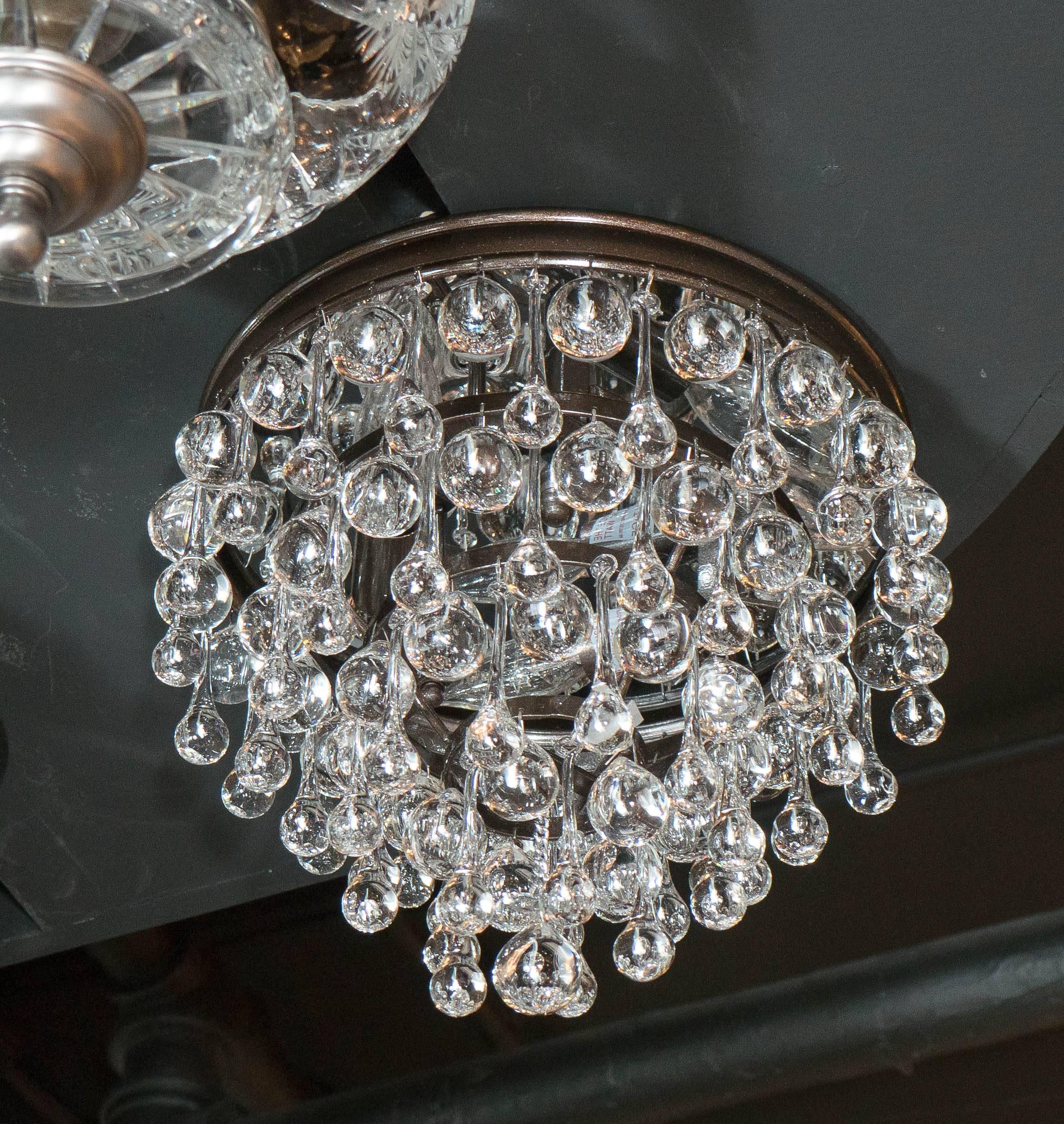 An elegant flush mount chandelier with contrasting crystal ball and teardrop glass segments in a radial pattern. The result is a very sparkling effect typical of Hollywood style and glamour. The fixture is chrome and the glass is handblown. This