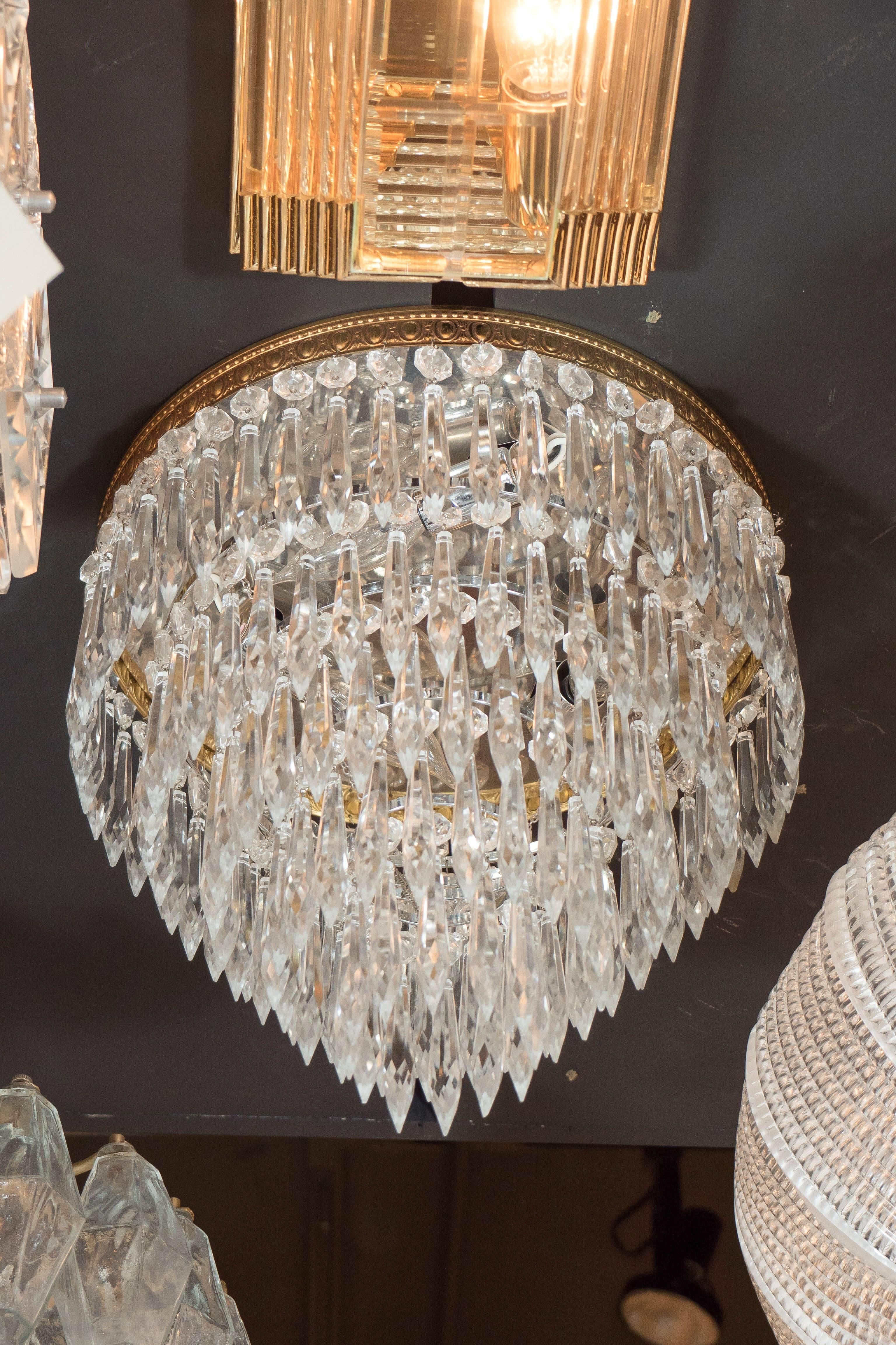 This elegant 1940's cut crystal flush mount chandelier features 5 tiers of hand-cut crystals in faceted pendant forms. The brass detailing features a beautiful pattern which contours the upper tier. A classic example of Hollywood Regency style and