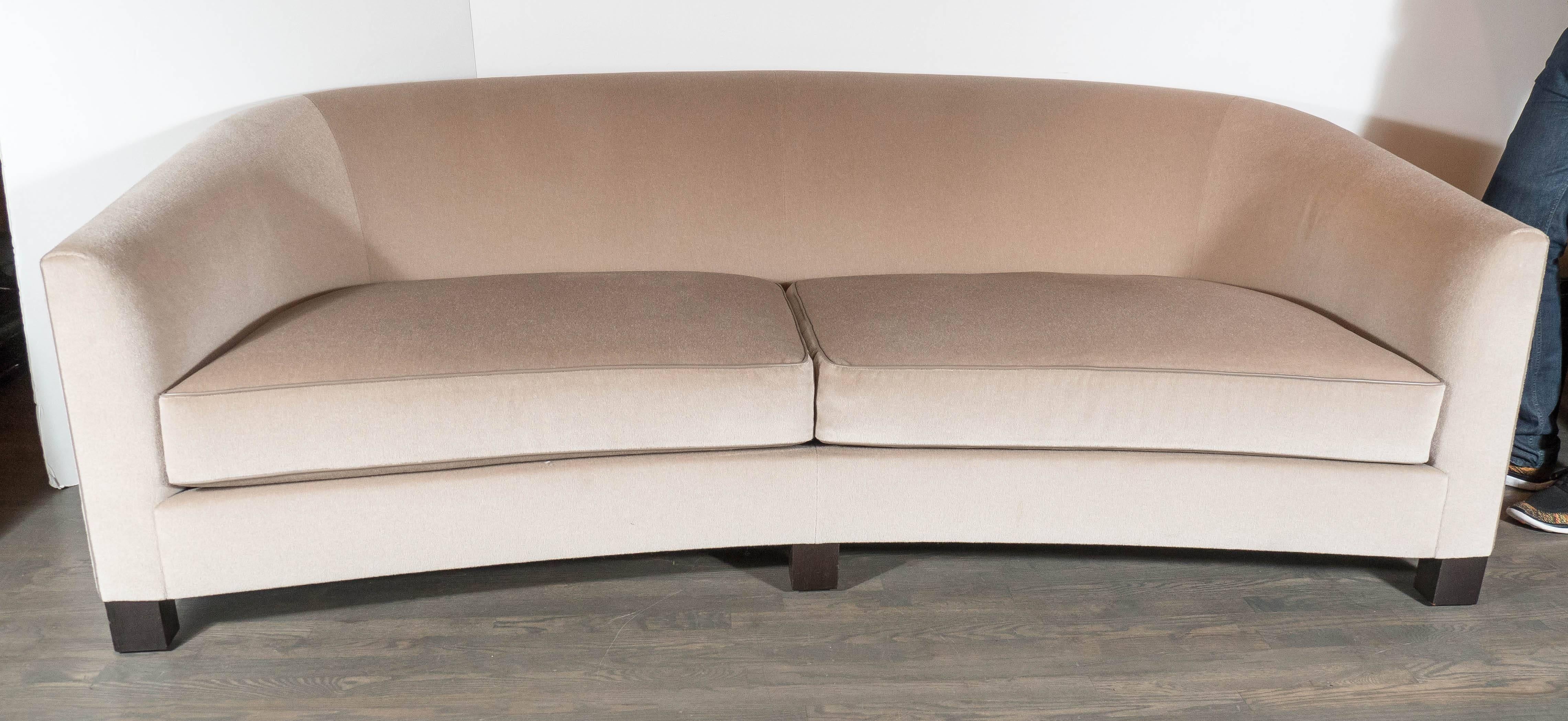 This classic  modernist Art Deco style sofa feature ebonized walnut legs, a bowed elegant classic front design all newly upholstered in an exquisite silk/wool camel mohair with taupe leather piping.This sofa is incredibly comfortable and uses the