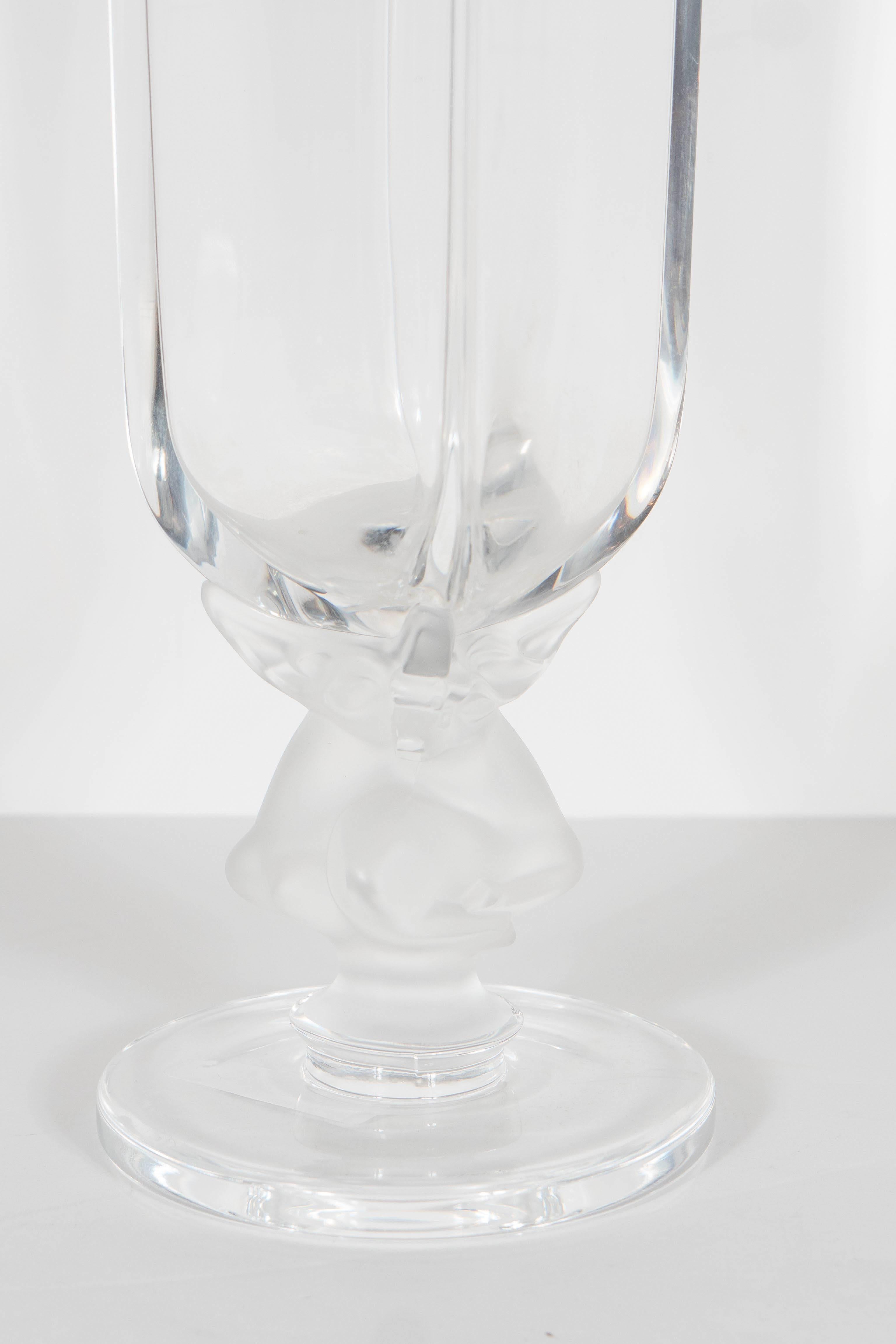This elegant Lalique crystal vase features a rectangular form sitting atop of a frosted glass support, which appears from a distance like amorphous organic sculptural forms. Upon closer inspection, however, one sees that they are perfectly