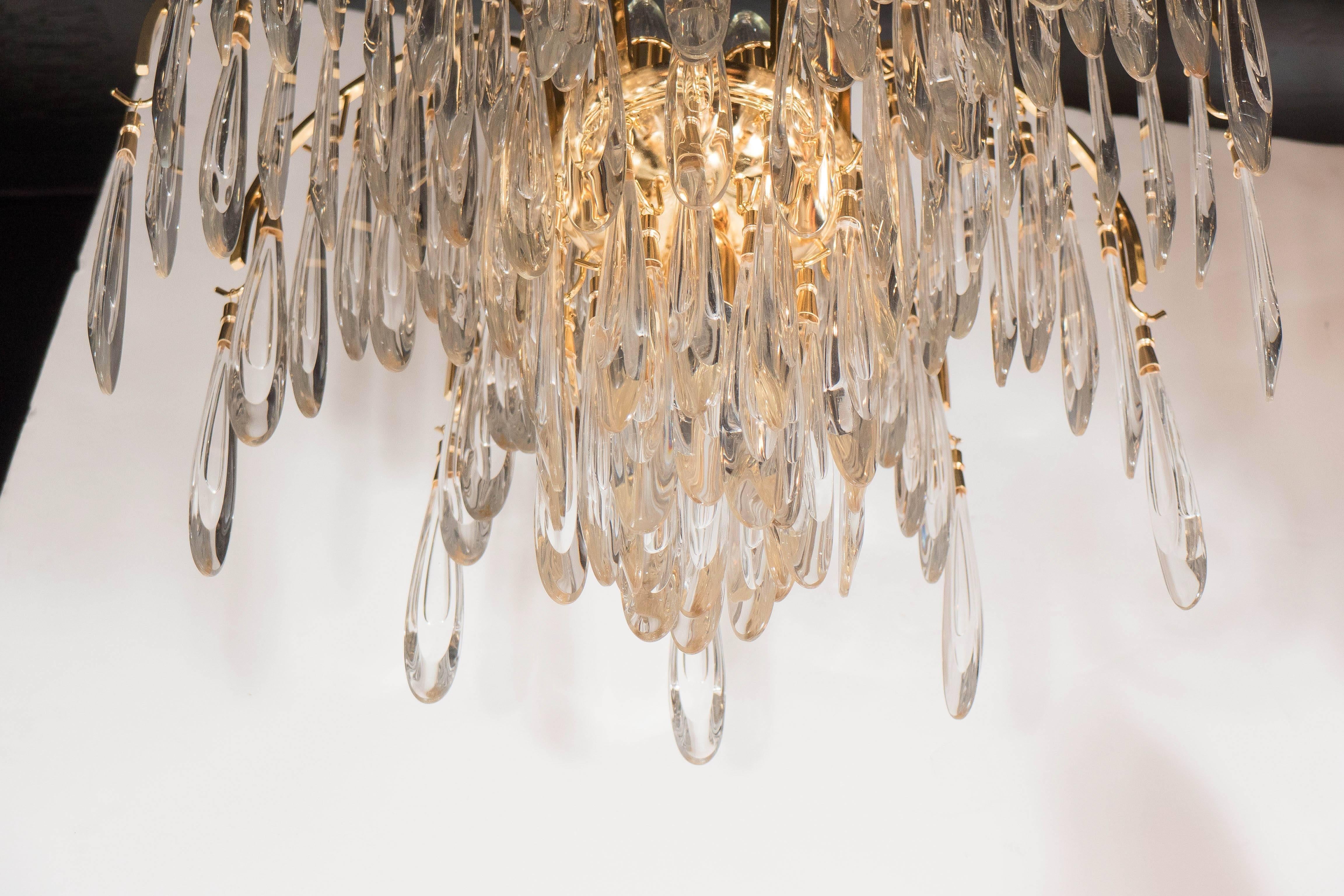 This stunning Mid-Century Modernist chandelier in the manner of Lobmeyr features a twelve-arm stylized palm tree design. The arm of the brass frame are draped with numerous feather shaped crystals and the interior is filled with a center of crystals