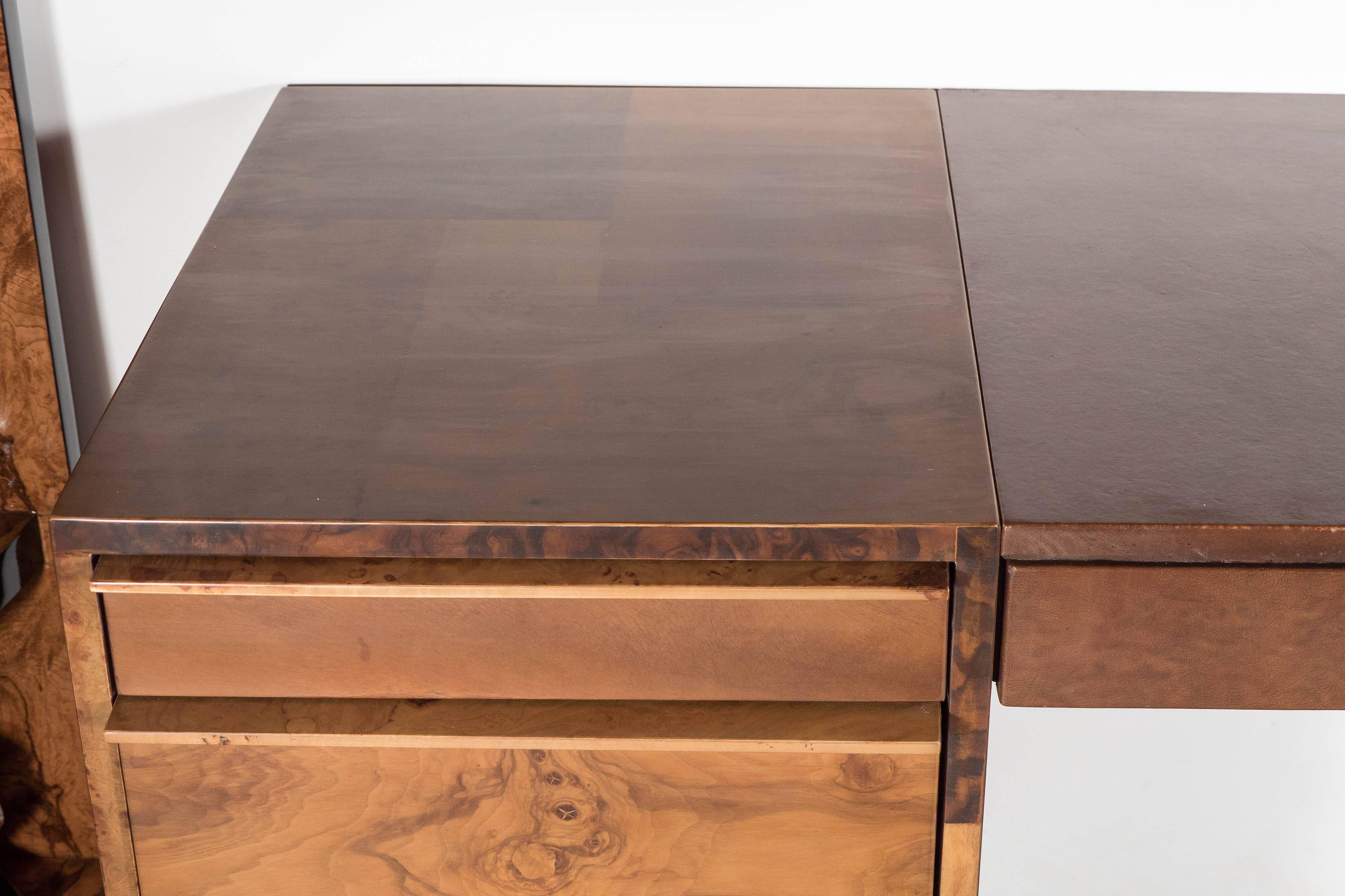 An exquisite Mid-Century Modernist executive desk in maple and olive burl wood patchwork design. This example has seven smooth-gliding drawers, two of which provide generous file storage, and a lovely rich cognac leather-clad inset top. This piece