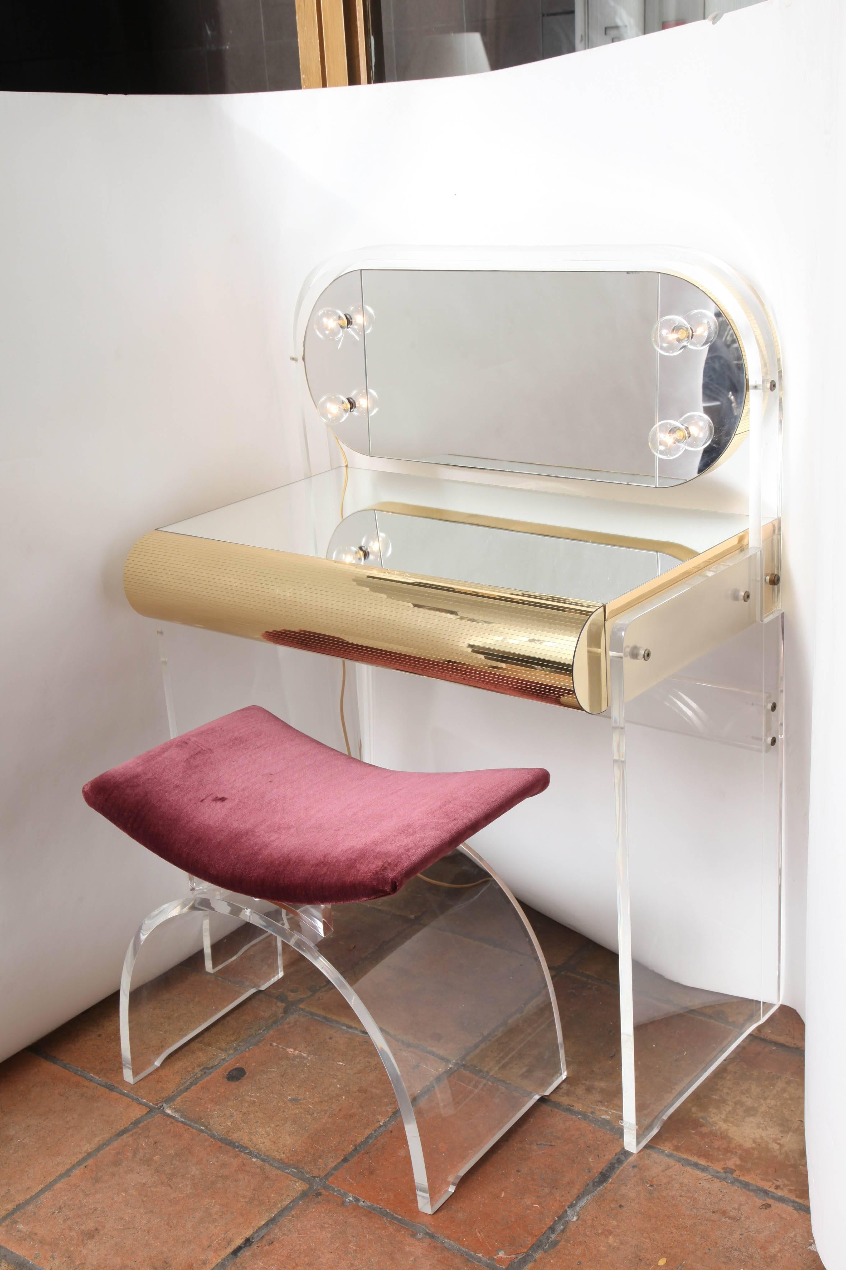 A fabulous mirrored Lucite vanity with matching stool and large single mirrored drawer. The vanity has a curved mirror with four lights framed in Lucite.
The Lucite in these pieces are excellent quality and not distressed or cloudy.
