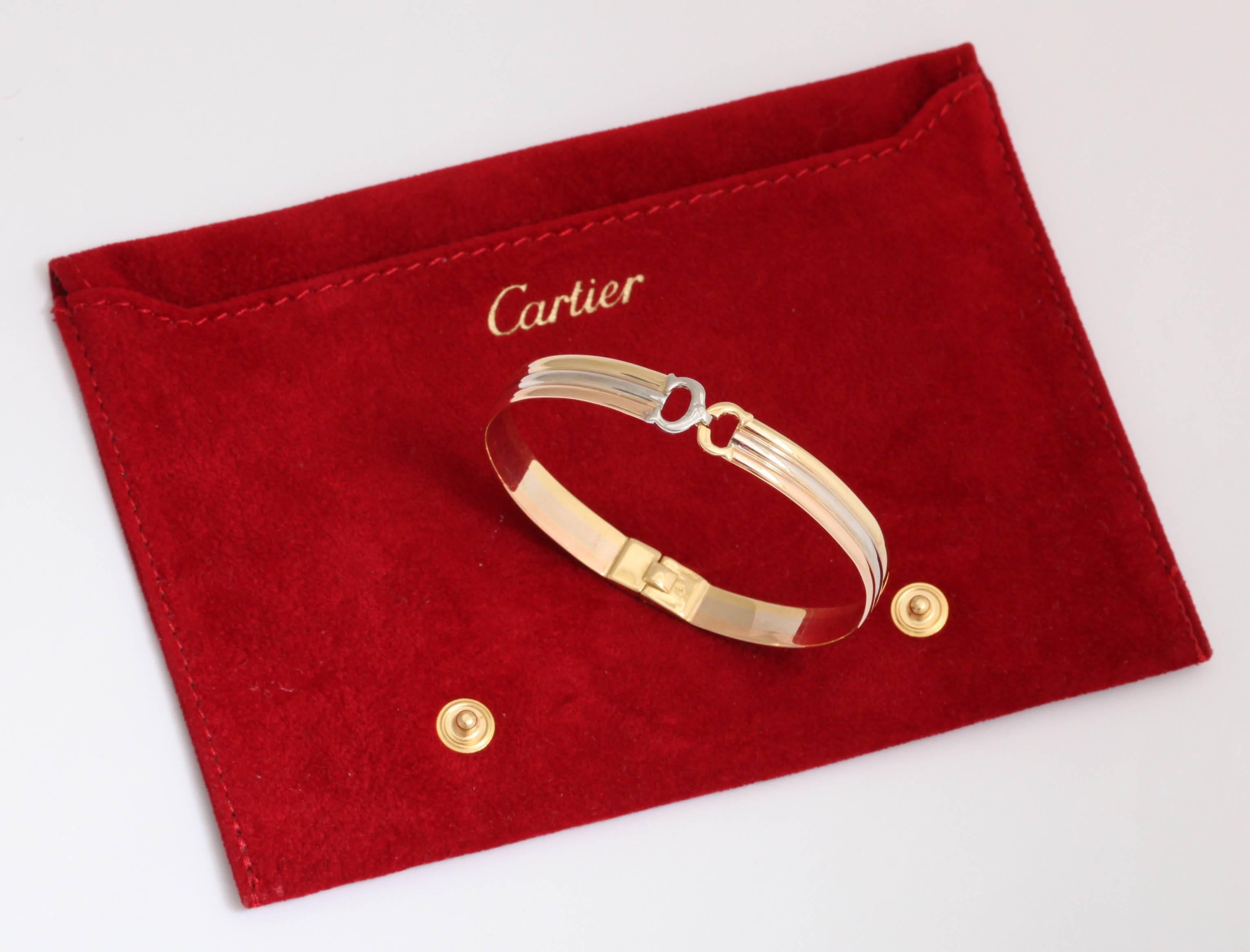 A Classic stylish 18-karat gold tricolor bangle by Cartier. The bangle ends in two intertwined C's, rose, white, yellow gold.