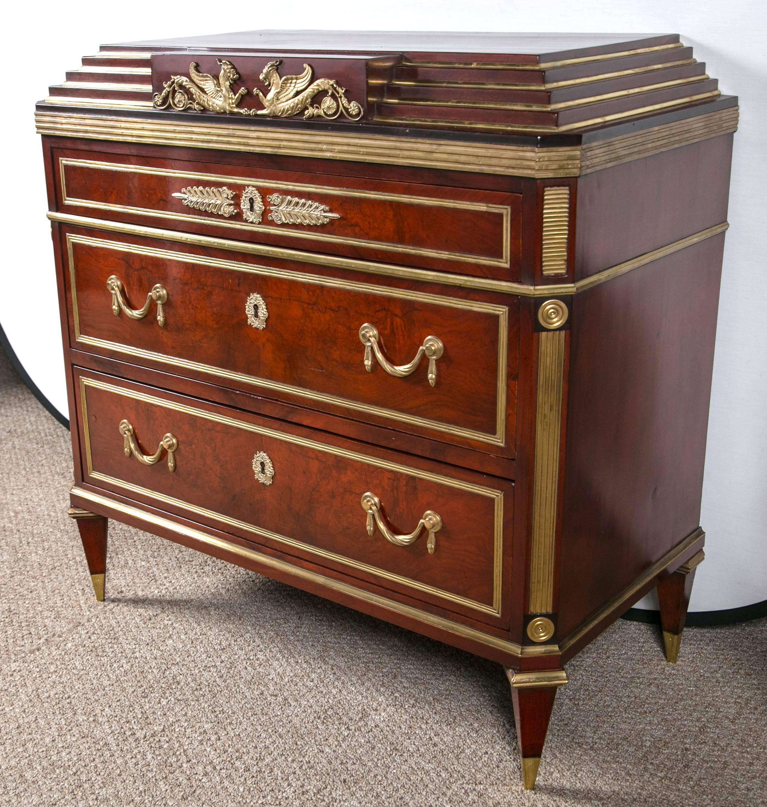 A Russian neoclassical step up commode. Three graduating drawers a true Fine antique recalling the age of old. The centerpiece consists of flying fighting dragons of bronze. The bronze mounts and drape design pulls are exquisite at every turn. The