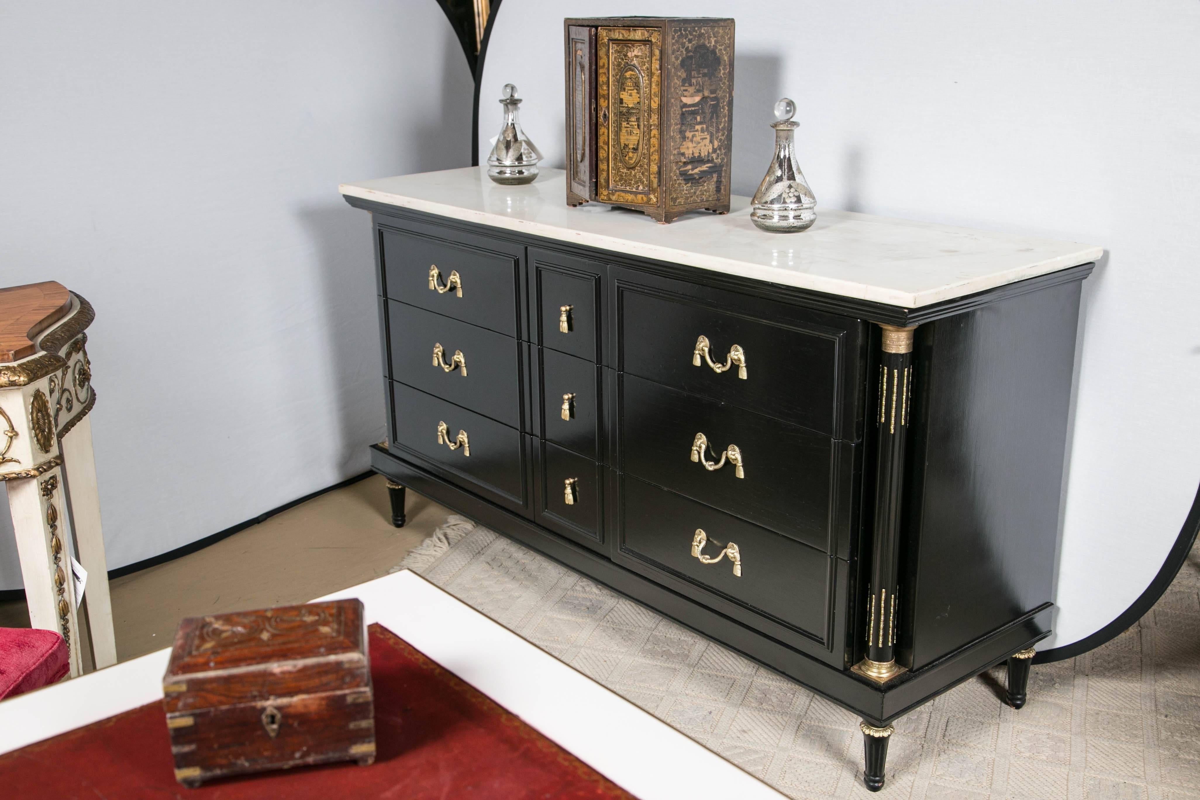 Louis XVI style marble-top ebonized dresser or sideboard by Maison Jansen. This finely detailed chest commode has three center drawers flaked by three larger drawers bearing a wonderful drape and tastle form group of bronze pulls. This is a fine
