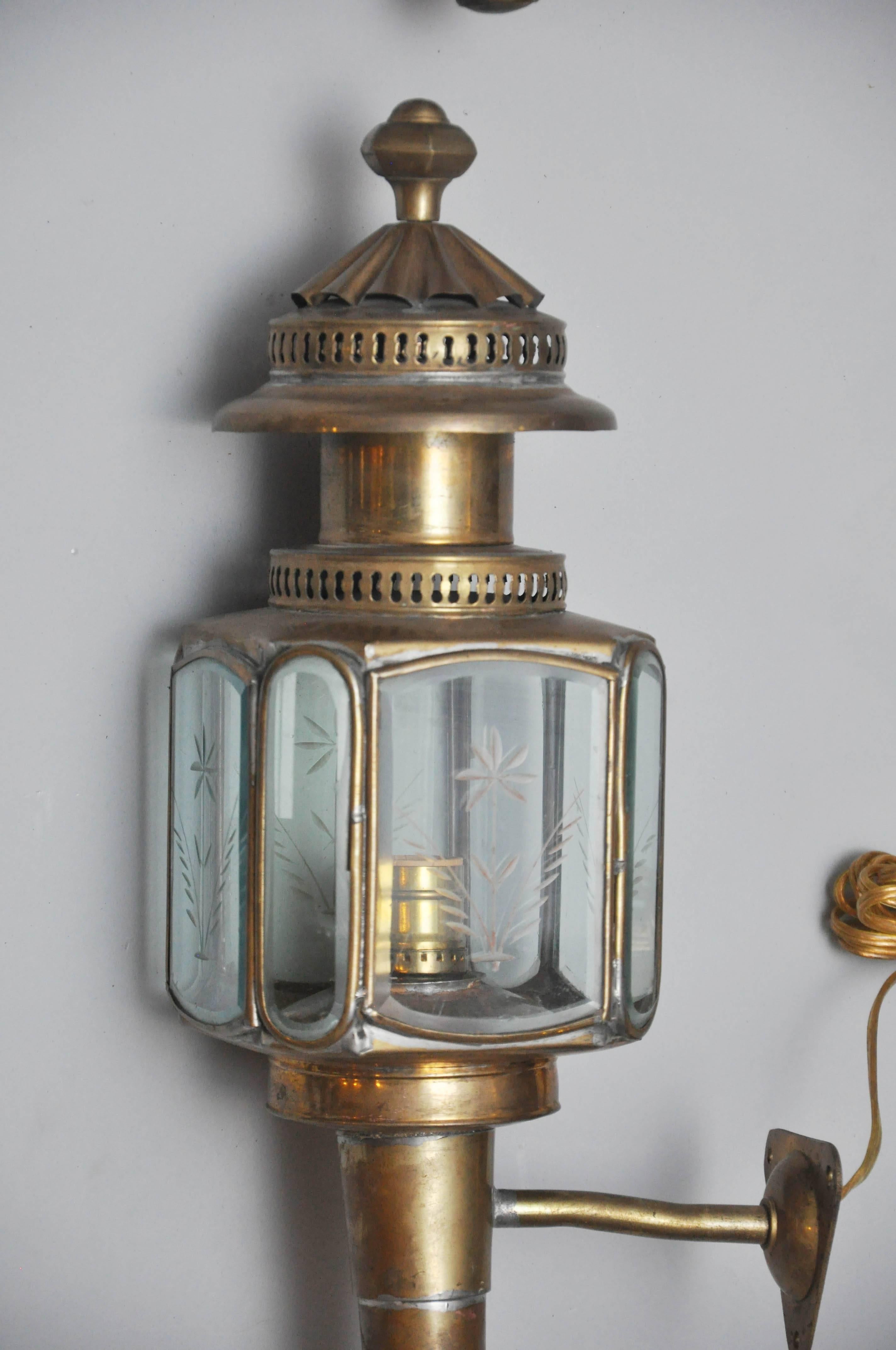 Pair of English brass carriage coach lanterns, hexagonal shaped body, five original glass panes with etched flower design, circular brass pierced roof with a finial at the crown, circular turned stem was used as an oil reservoir. Coach lights were