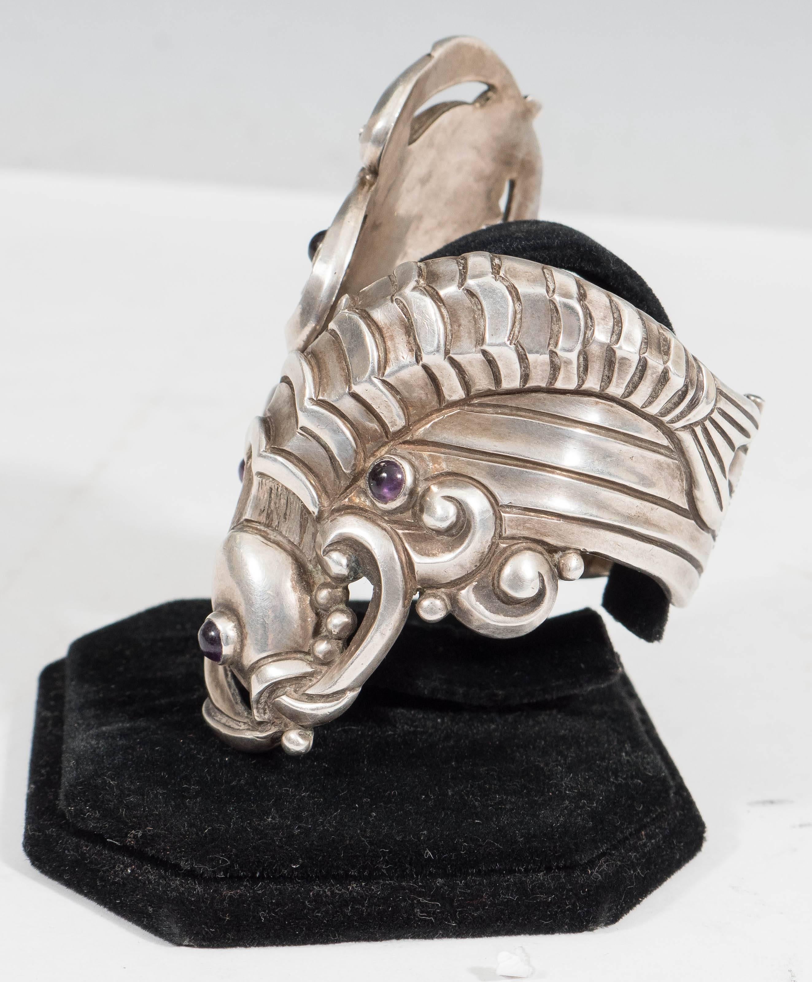 This vintage sterling silver clamper bracelet, produced in Mexico, circa 1940s by Margot van Voorhies Carr (otherwise 'Margot De Taxco'), features two Japanese inspired repousse koi fish, detailed with cabochon amethyst stones as their eyes and