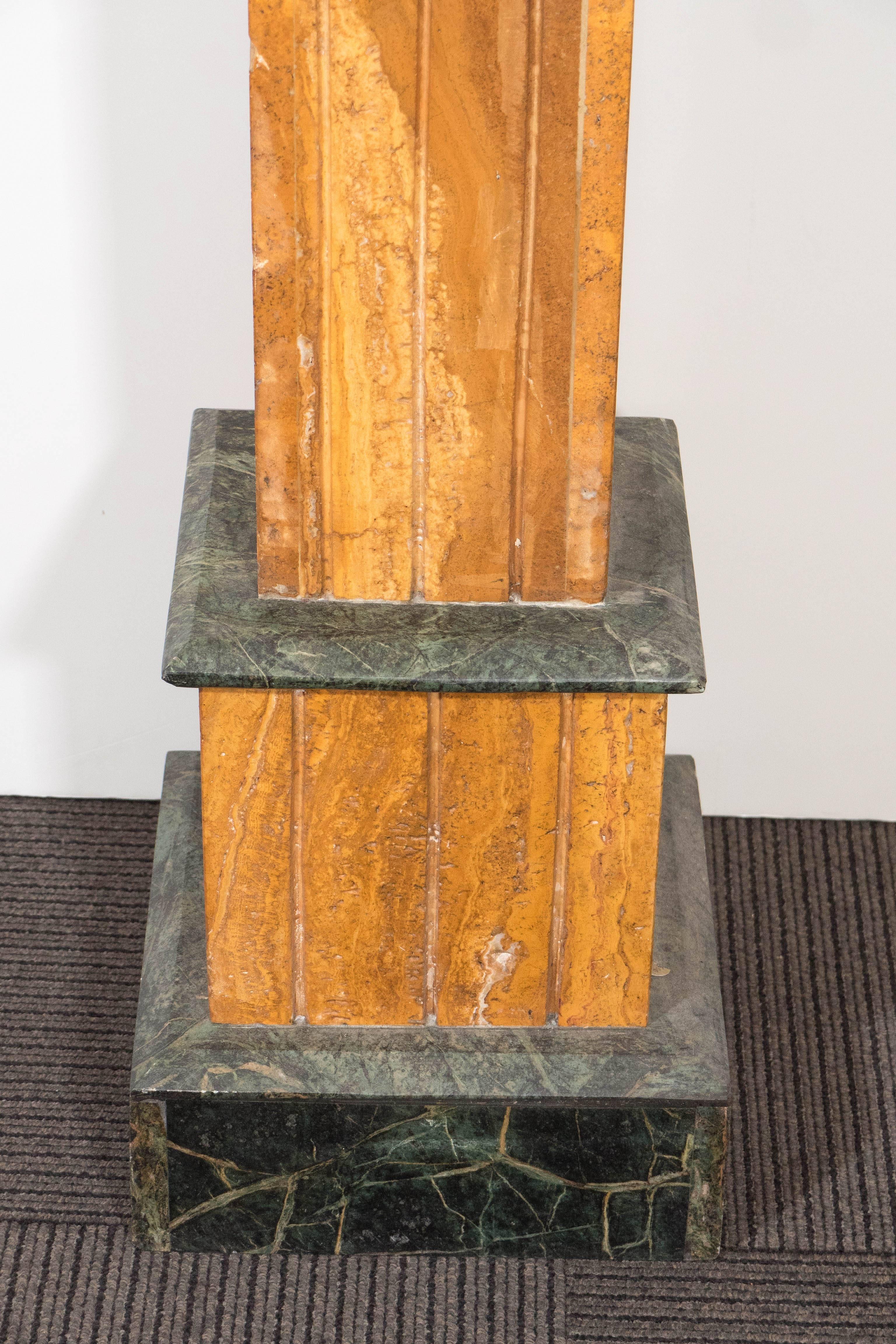 A vintage pair of pedestals, produced circa 1930s, each with three sections of square, fluted travertine pillars, with bright yellow finish, accented with verde marble top and base. Good vintage condition, with age appropriate wear, and very slight