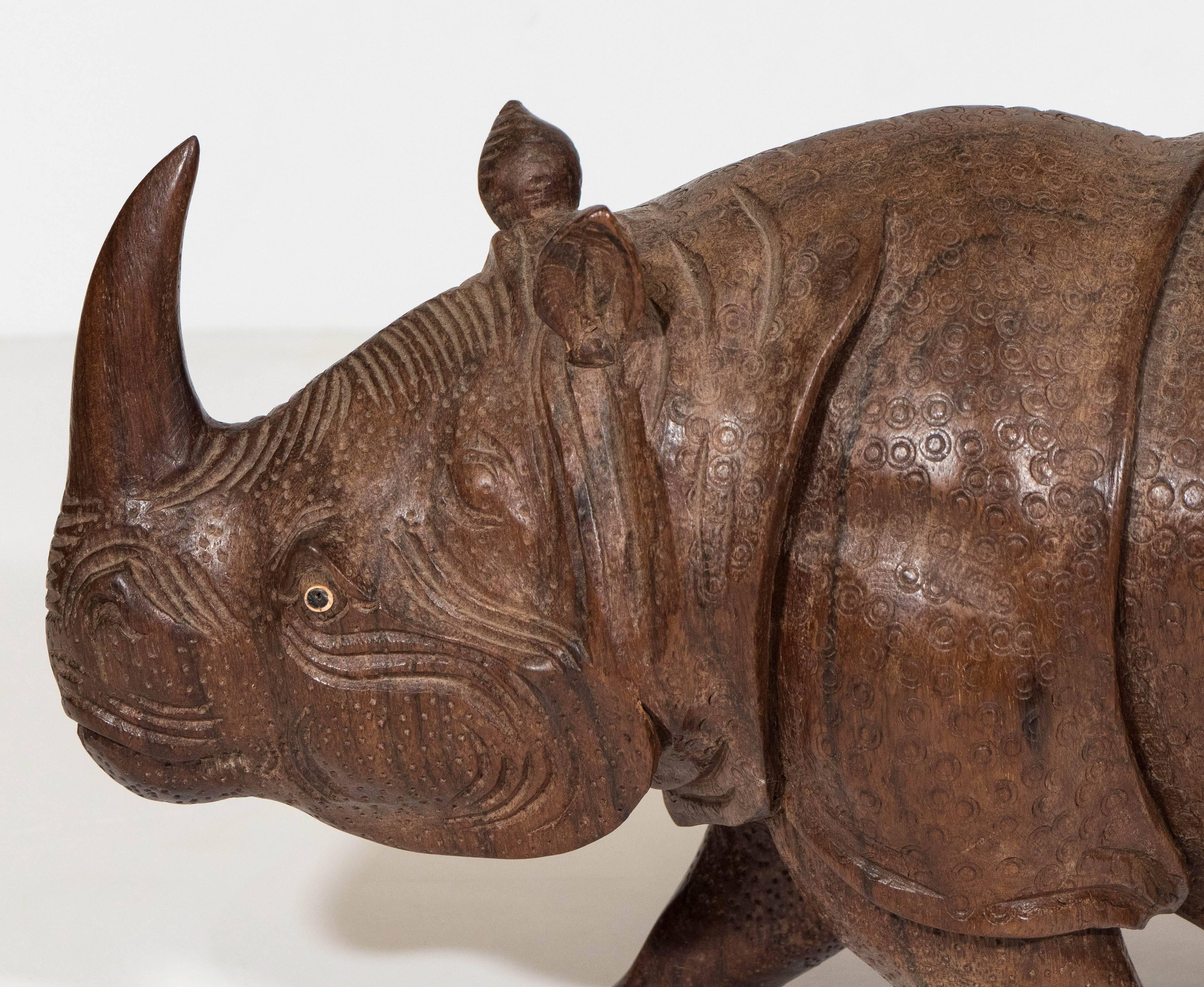 A vintage intricately detailed sculpture of a rhino in carved wood. This piece remains in very good condition, consistent with age and use.