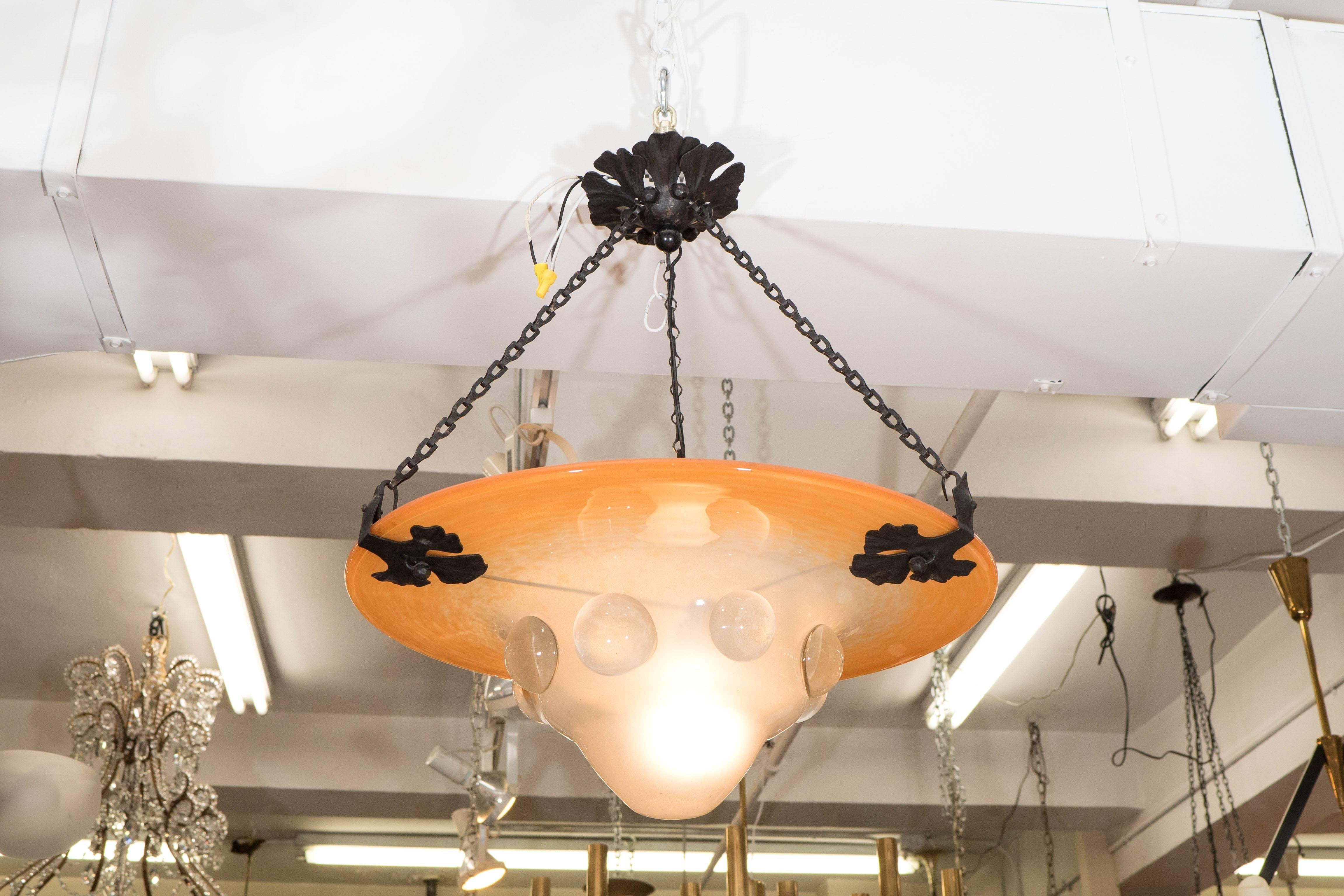 A vintage French Art Nouveau style chandelier, produced circa 1920s-1930s by Schneider Glass, with convex glass shade in ombre tones of mottled peach to frosted white, decorated with clear globes, suspended by three wrought iron chains, the support