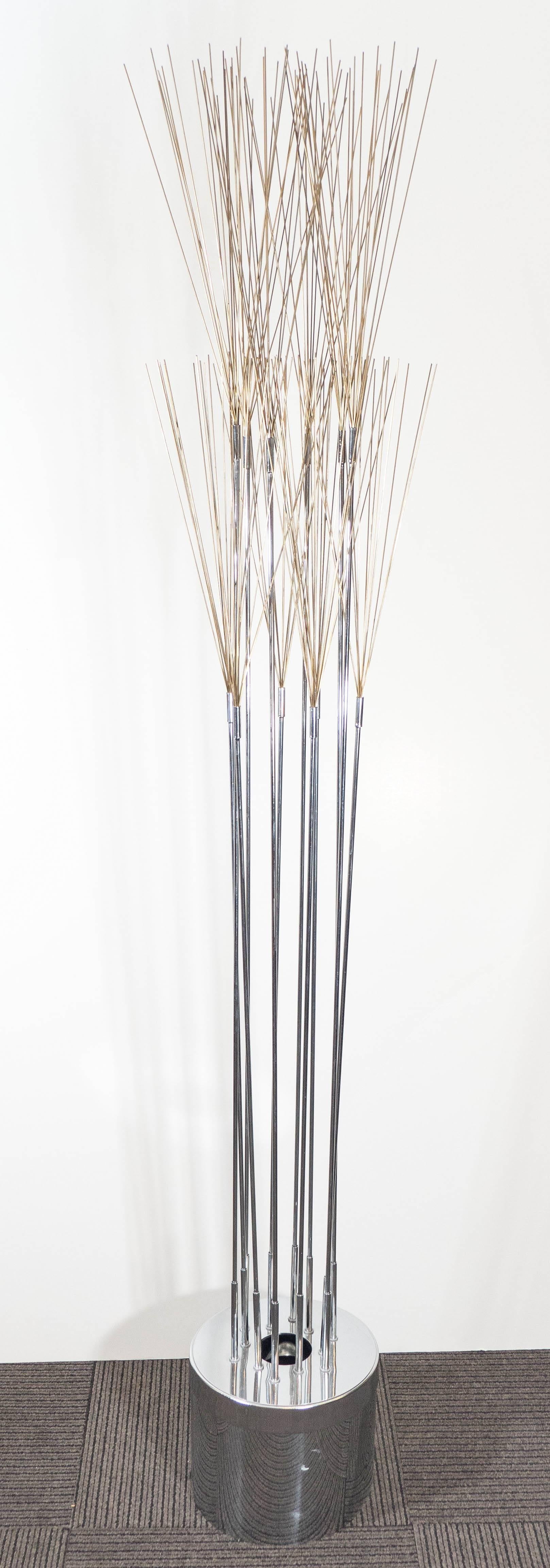 A Curtis Jere Kinetic sculpture and floor lamp circa 1970s, with lengthy spires in mixed metal, extending from a cylindrical illuminating base in polished chrome. Wiring and socket to US standard, requires a single bulb; includes rotary on-off light