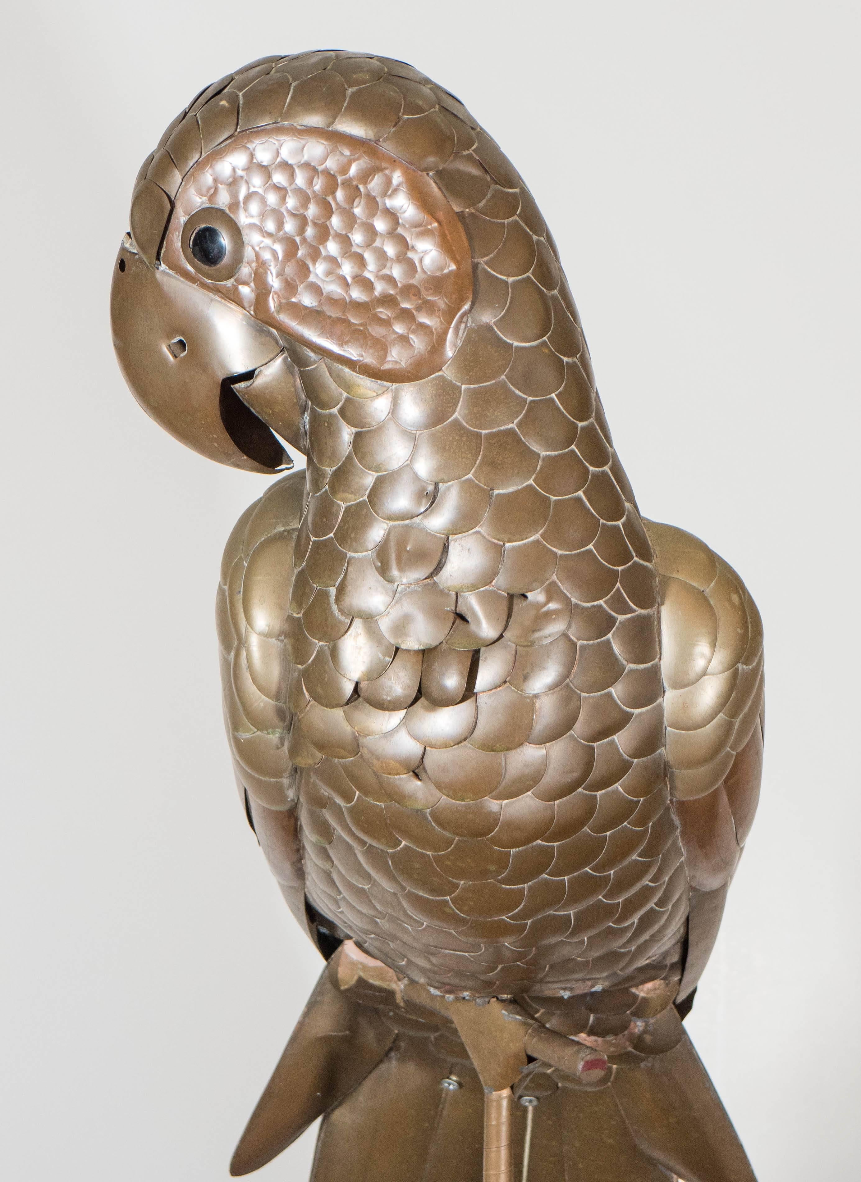 A vintage sculpture of a parrot, perched on a tripod stand, produced by Mexican artist Sergio Bustamante, in brass with copper accents. Good condition, any present wear consistent with age.
