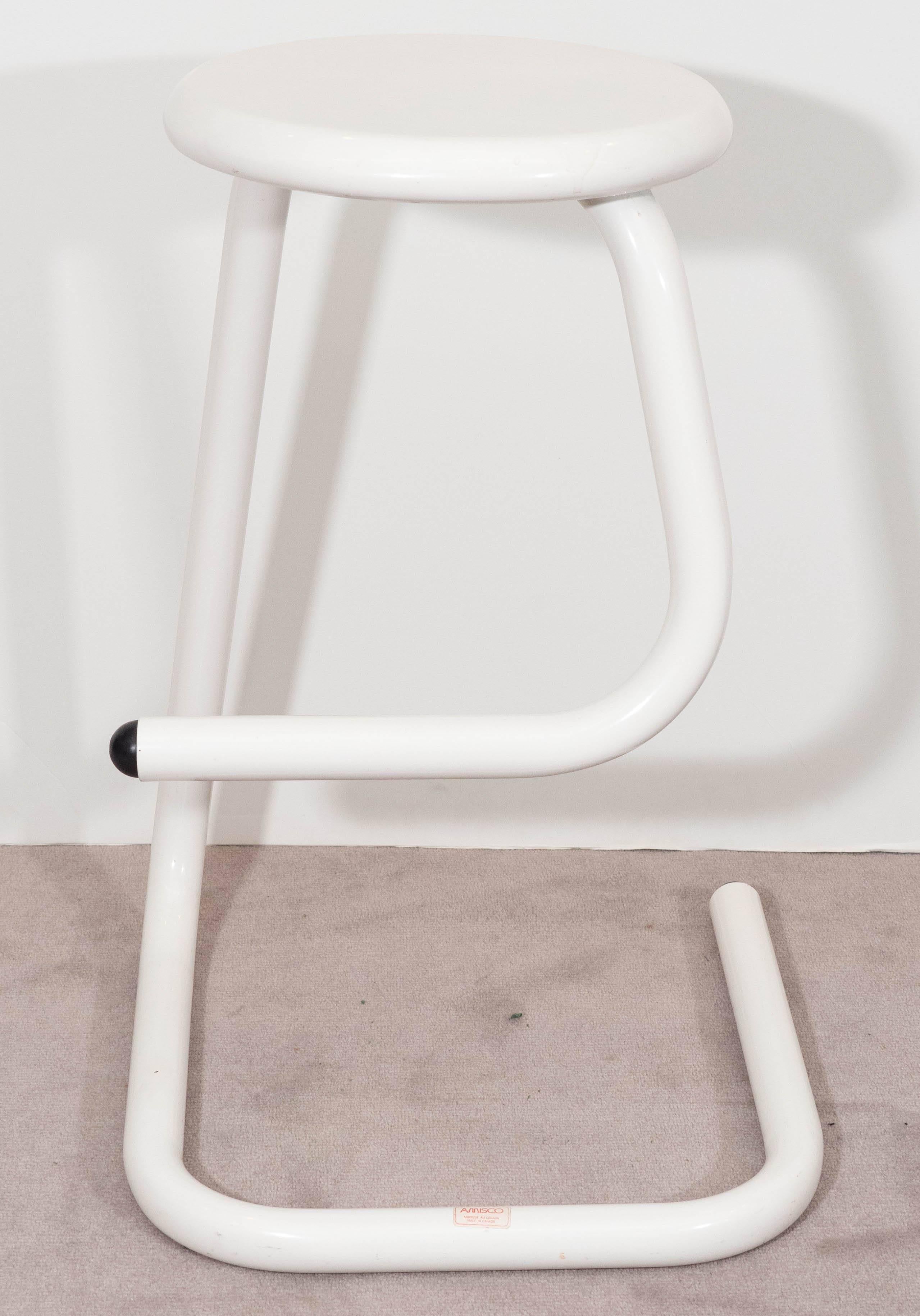 A pair of vintage highly modernistic metal bar stools, produced in Canada, circa 1960s to 1970s by Les Industries Amisco, each in white, the seats set on a winding, single paperclip form tubular base. Markings include label [AMISCO/Fabrique au