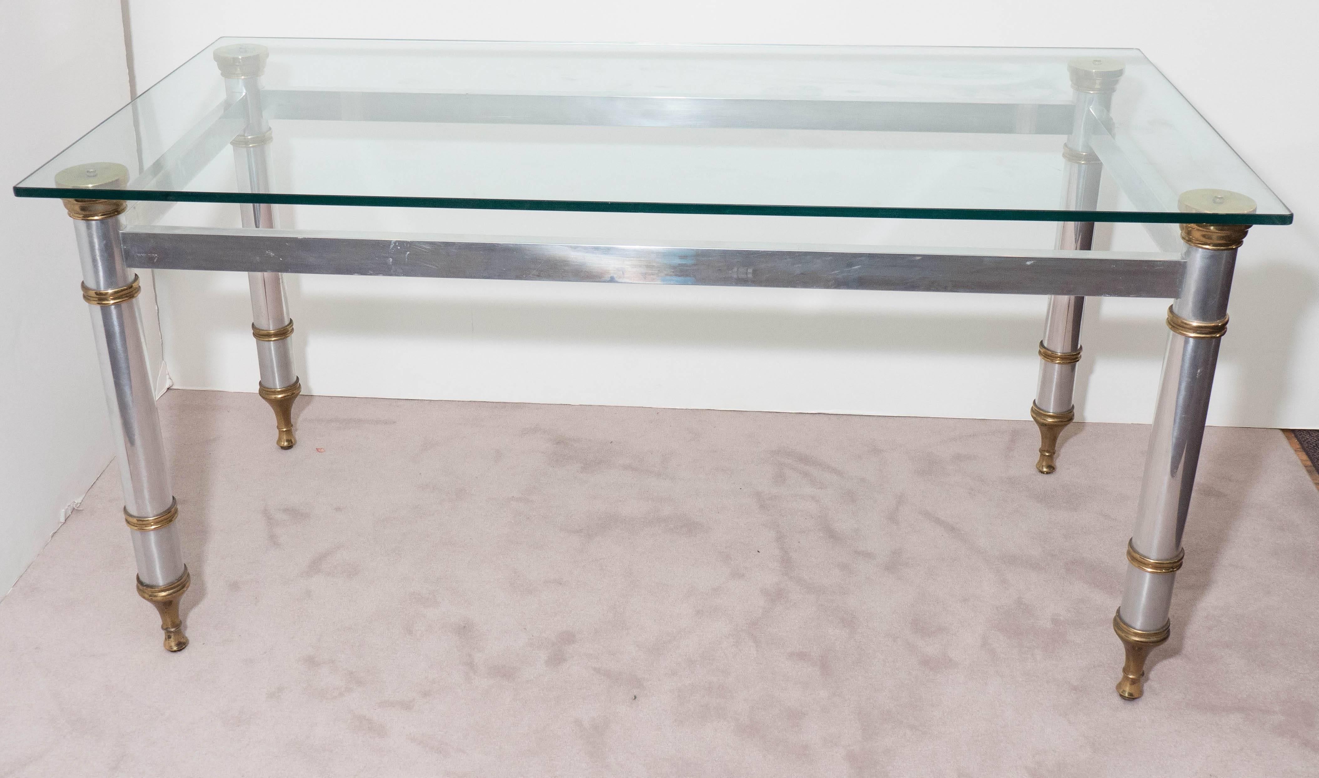 A highly versatile glass top table, influenced by the Directoire style, which can alternate as a dining table or desk, produced circa 1960s by Maison Jansen of Paris (signed), on steel base and tapered legs, accented with brass. Markings include