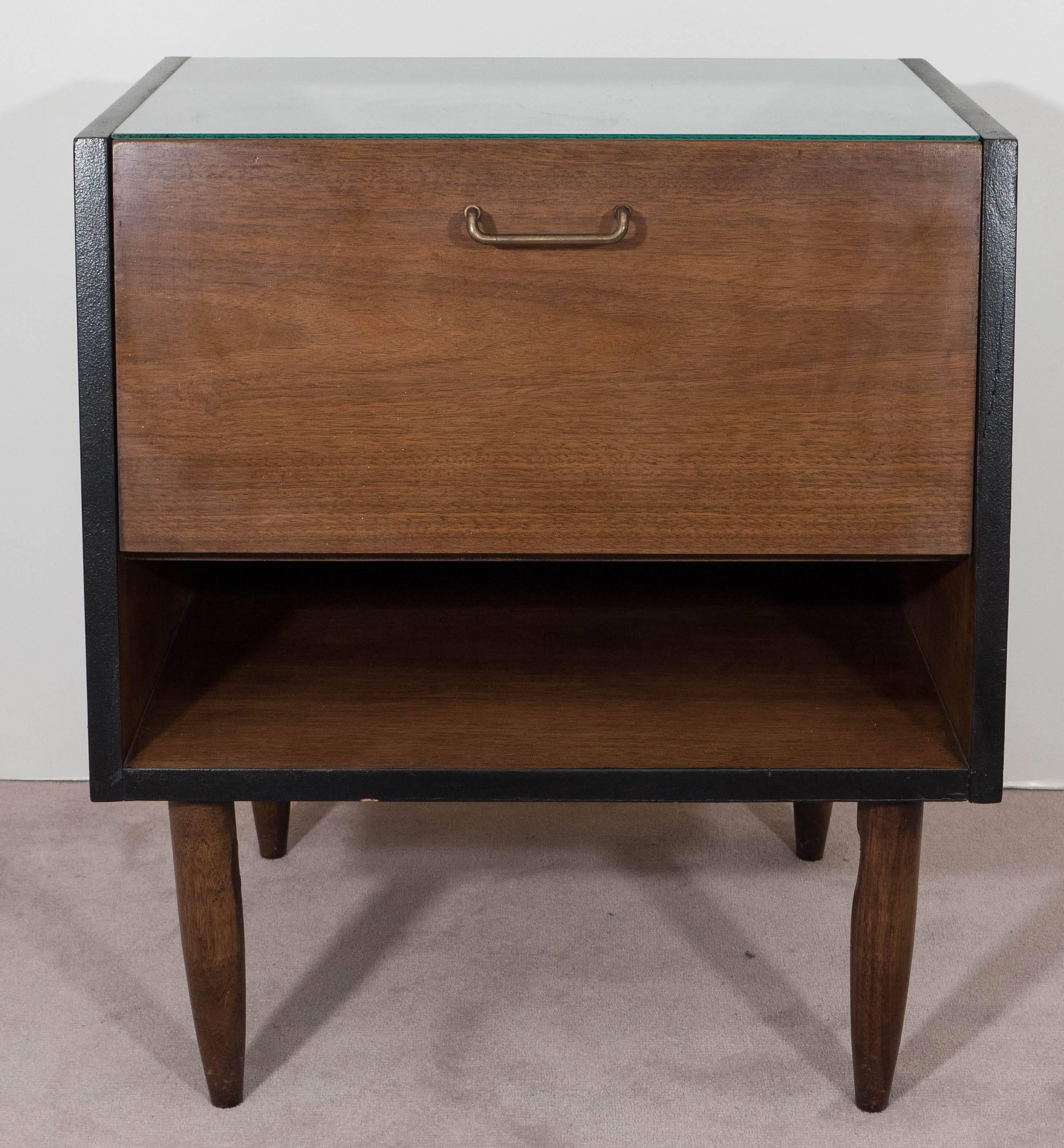 This vintage pair of wooden nightstands, designed by Merton Gershun for the American of Martinsville 'Dania Collection', produced circa 1950s-1960s, comes with laminated sides and top, standing on tapered legs. Included are drop front doors and