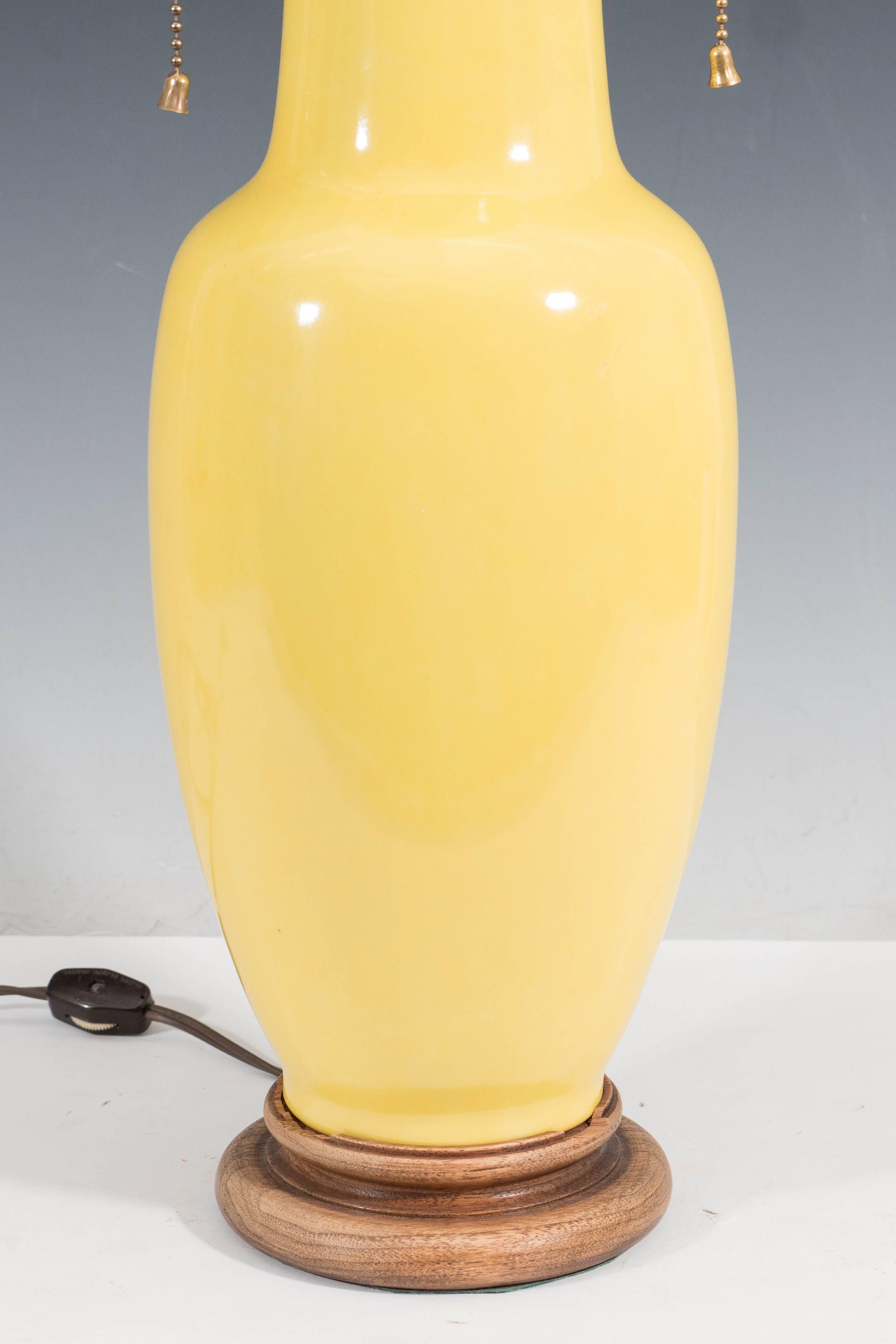A pair of vintage, ceramic yellow table lamps, each with double cluster sockets (two pull chains included) and ball finial on elongated stem and cover in brass, above a baluster form body, styled after a Chinese ginger jar, on circular wood base.