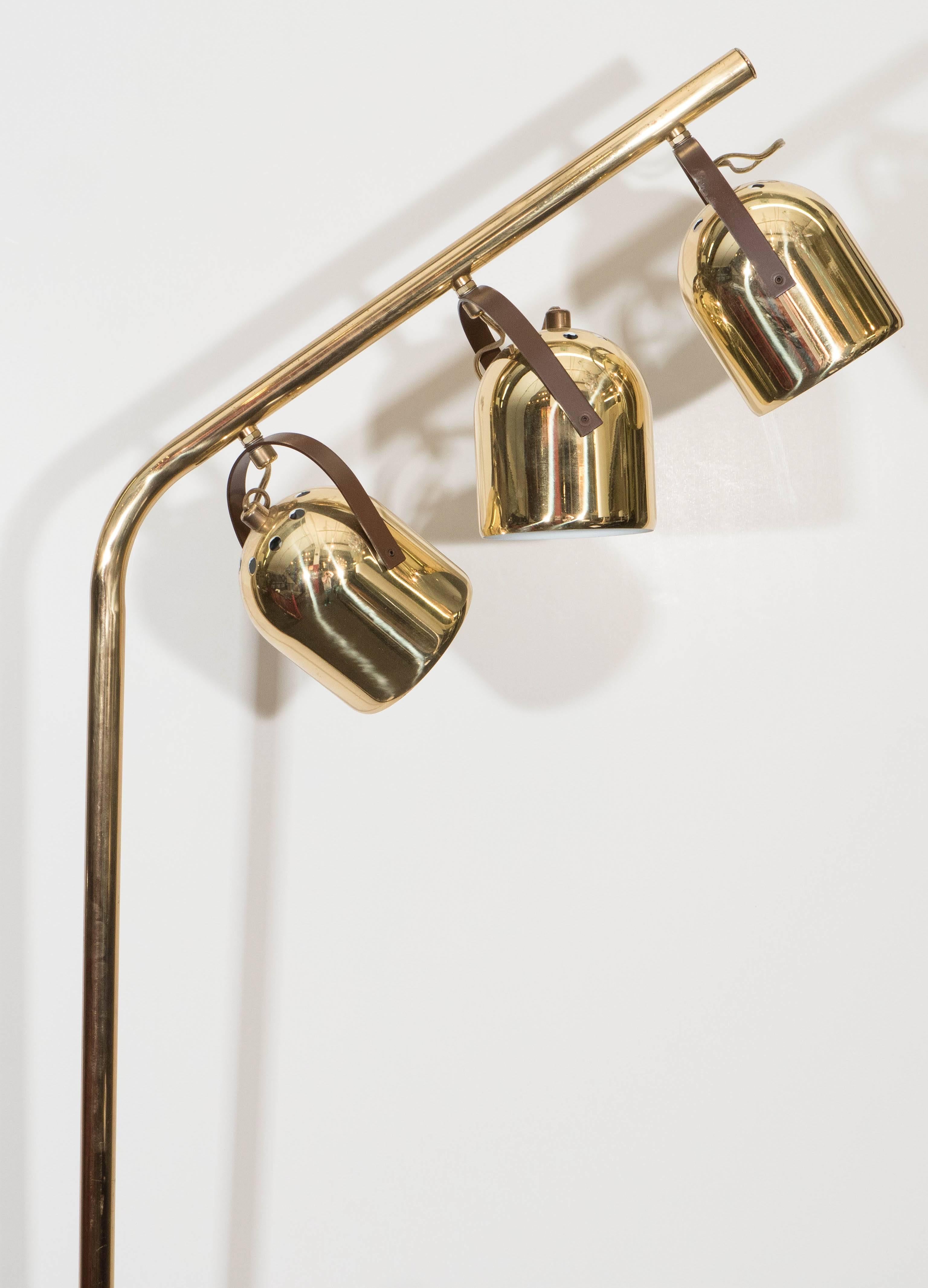This vintage floor lamp by Koch & Lowy, comes in polished brass, with three pivoting rounded light shades, attached to an artfully bent stem, on a circular base; on/off switch included on stem. Very good overall condition, present wear