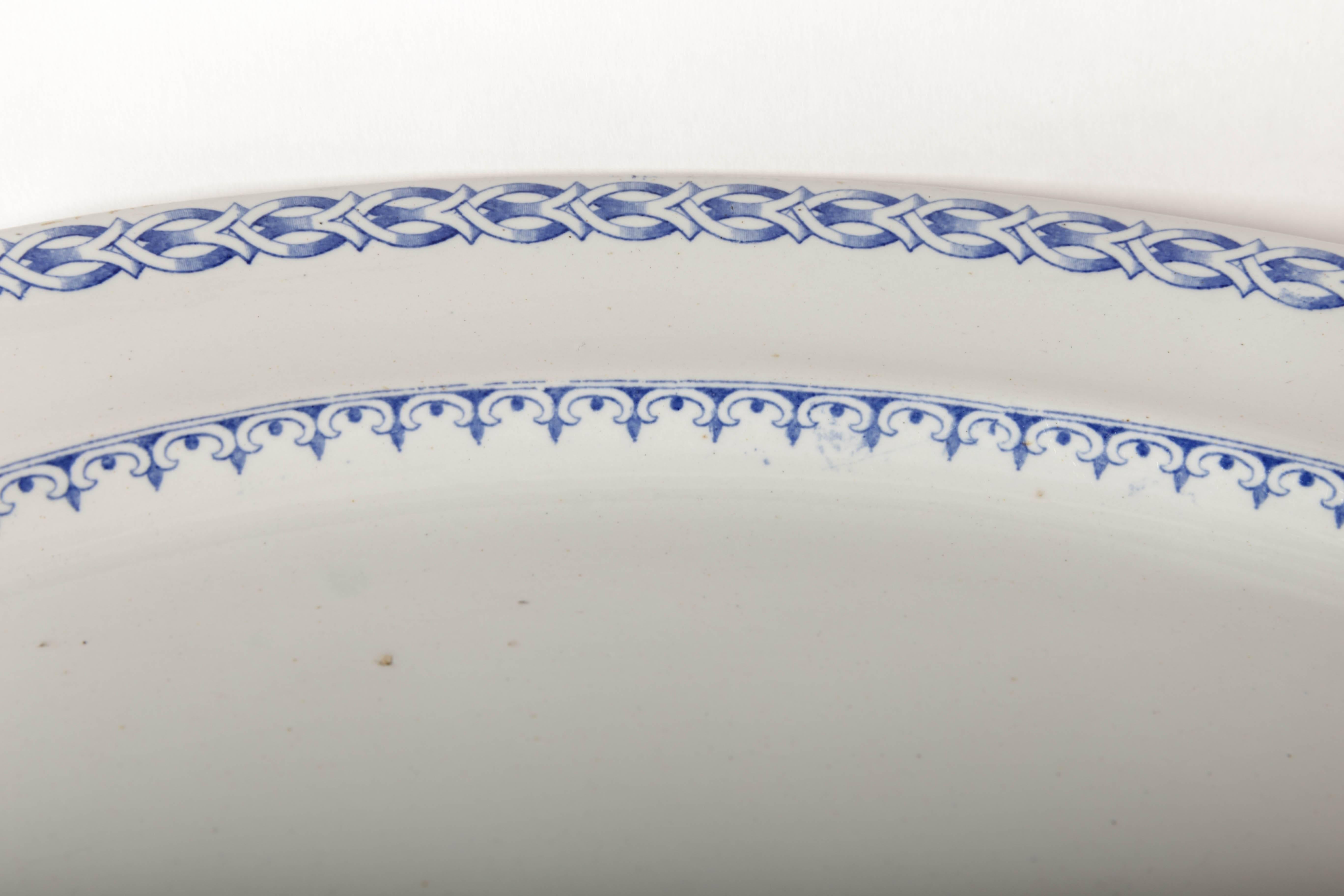 Large oval English Davenport transfer ware platter. The outer rim consists of a simple design of interlocking stylized ovals terminating with y's that could be fish. The lower rim forms oval arches with dots and points. The back is stamped with a