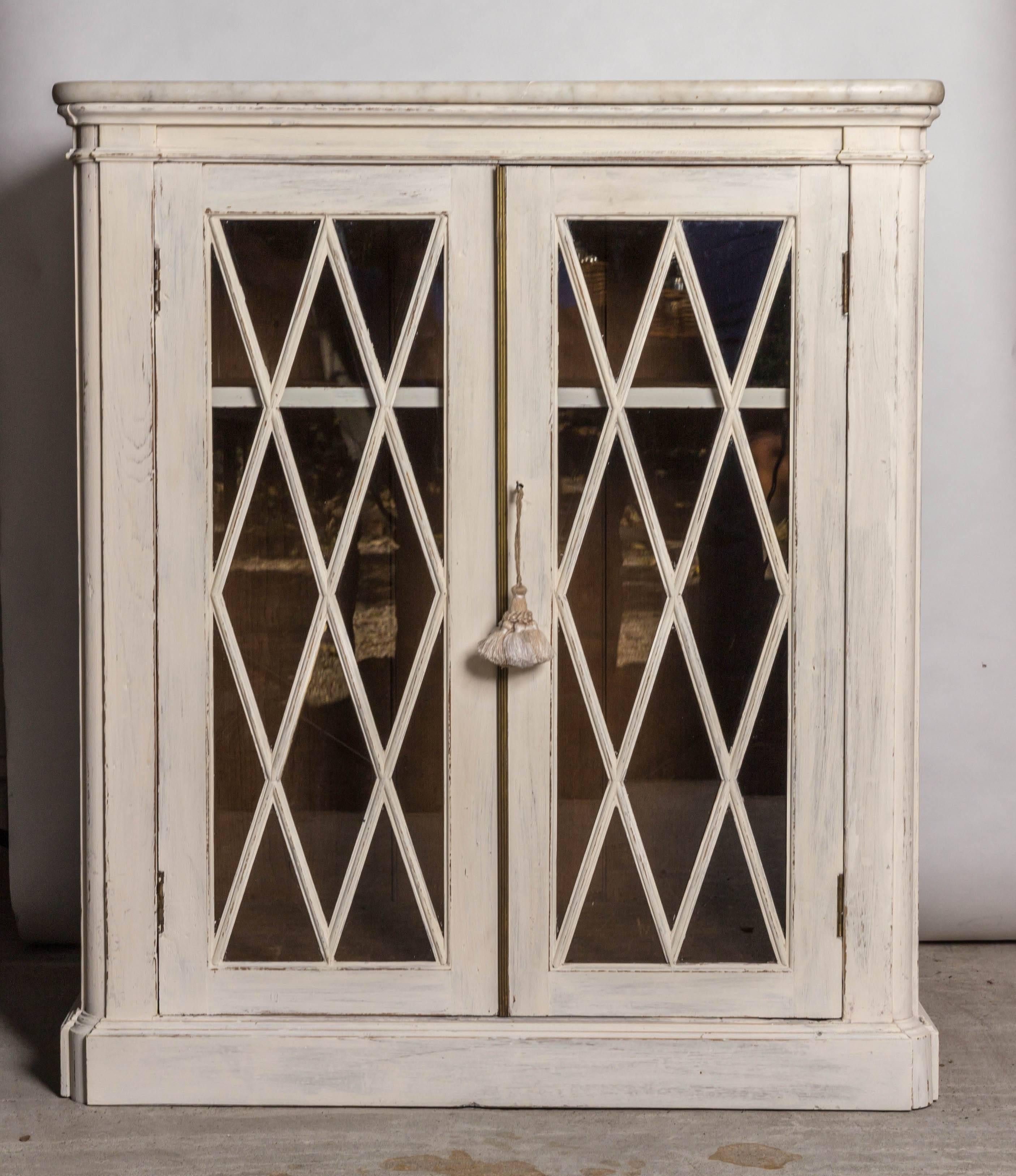 English 19th century painted pine marble-top cabinet with diamond pattern glazed doors. The cabinet is painted in the Swedish Gustavian Style with a distressed pale grey off-white color. A handsome utilitarian piece of furniture that can serve as a