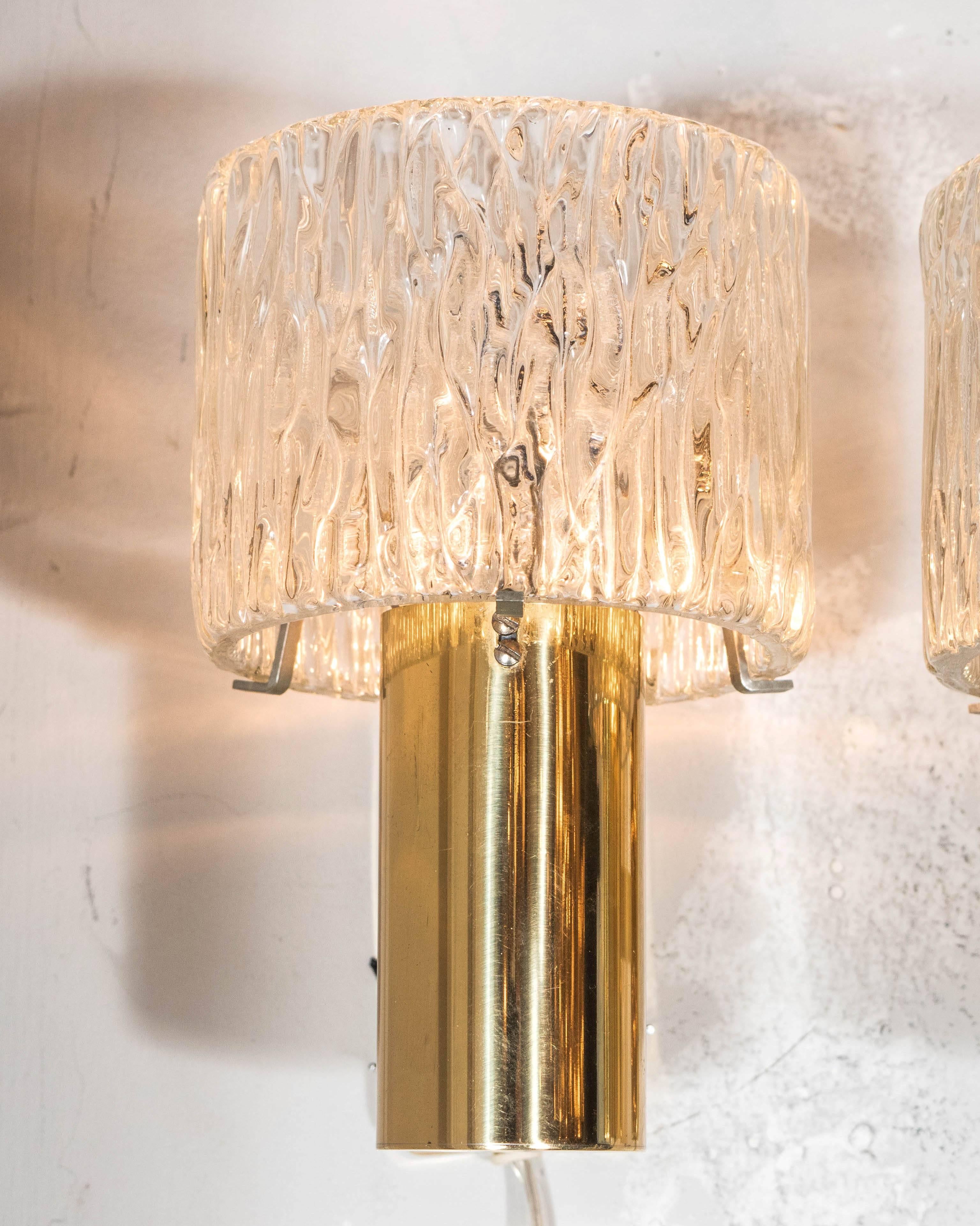A very elegant and unusual pair of textured glass sconces supported by a brass base by Carl Fagerlund for Orrefors. Tubular glass shades encompassing the frame rest atop polished brass tube bases. Completely rewired and in excellent condition.