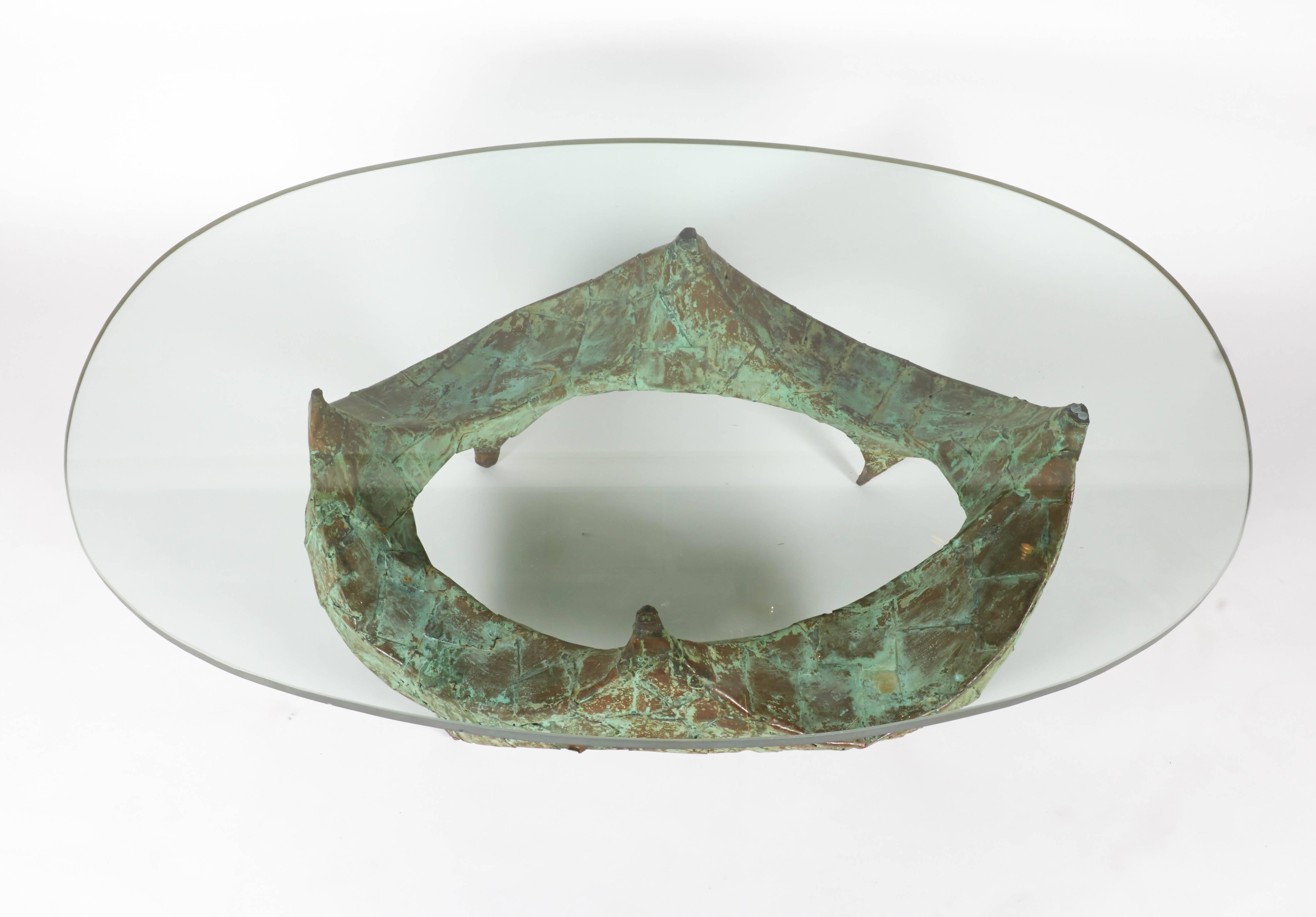 A sculptural hand-hammered verdigris copper coffee table with the original 3/4 in glass.
    