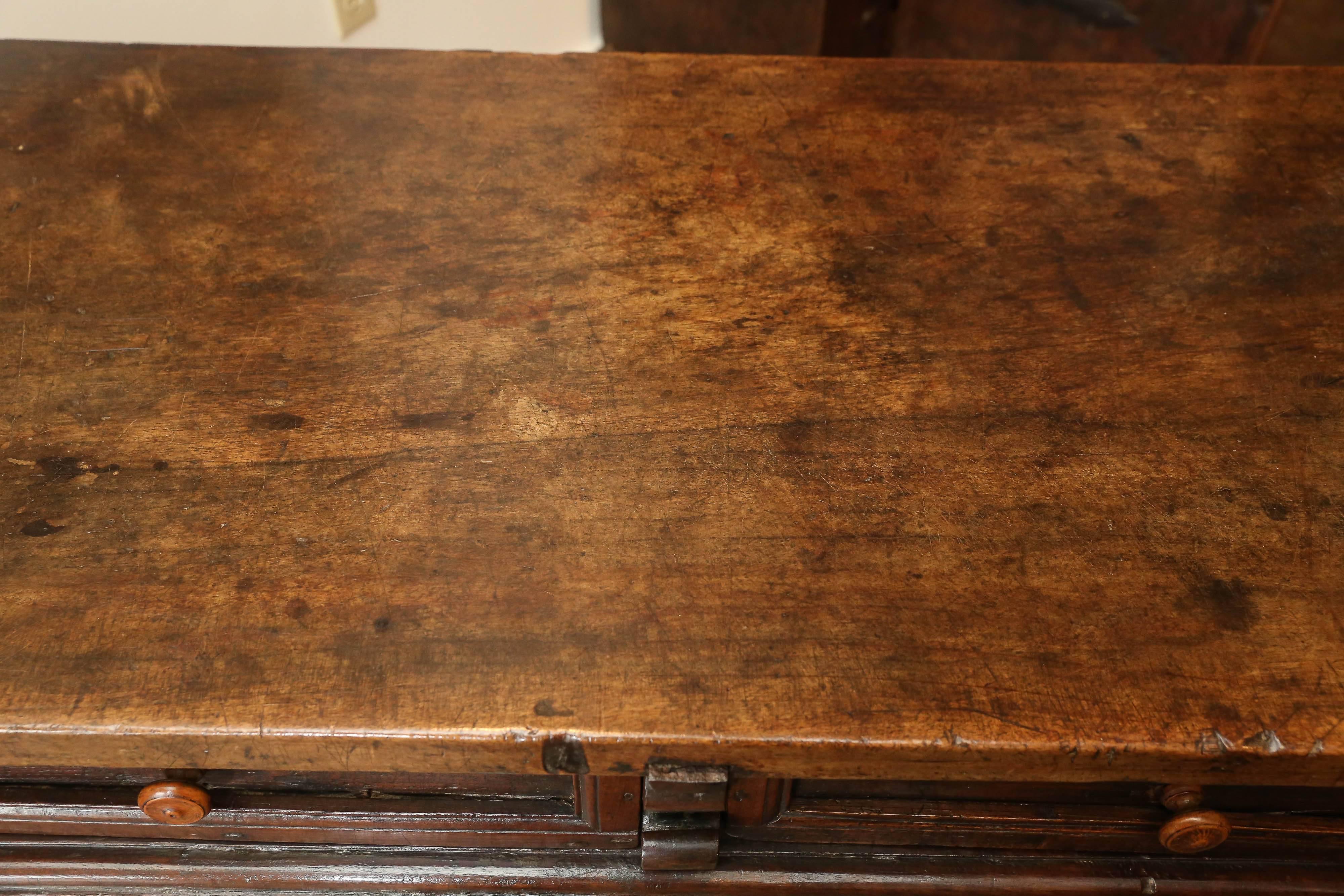 konsolentisch aus spanischem Nussbaumholz des 17. Jahrhunderts mit zwei Schubladen, gespreizten Beinen und eiserner Bahre. Die Platte ist aus einem einzigen Stück Nussbaumholz gefertigt.