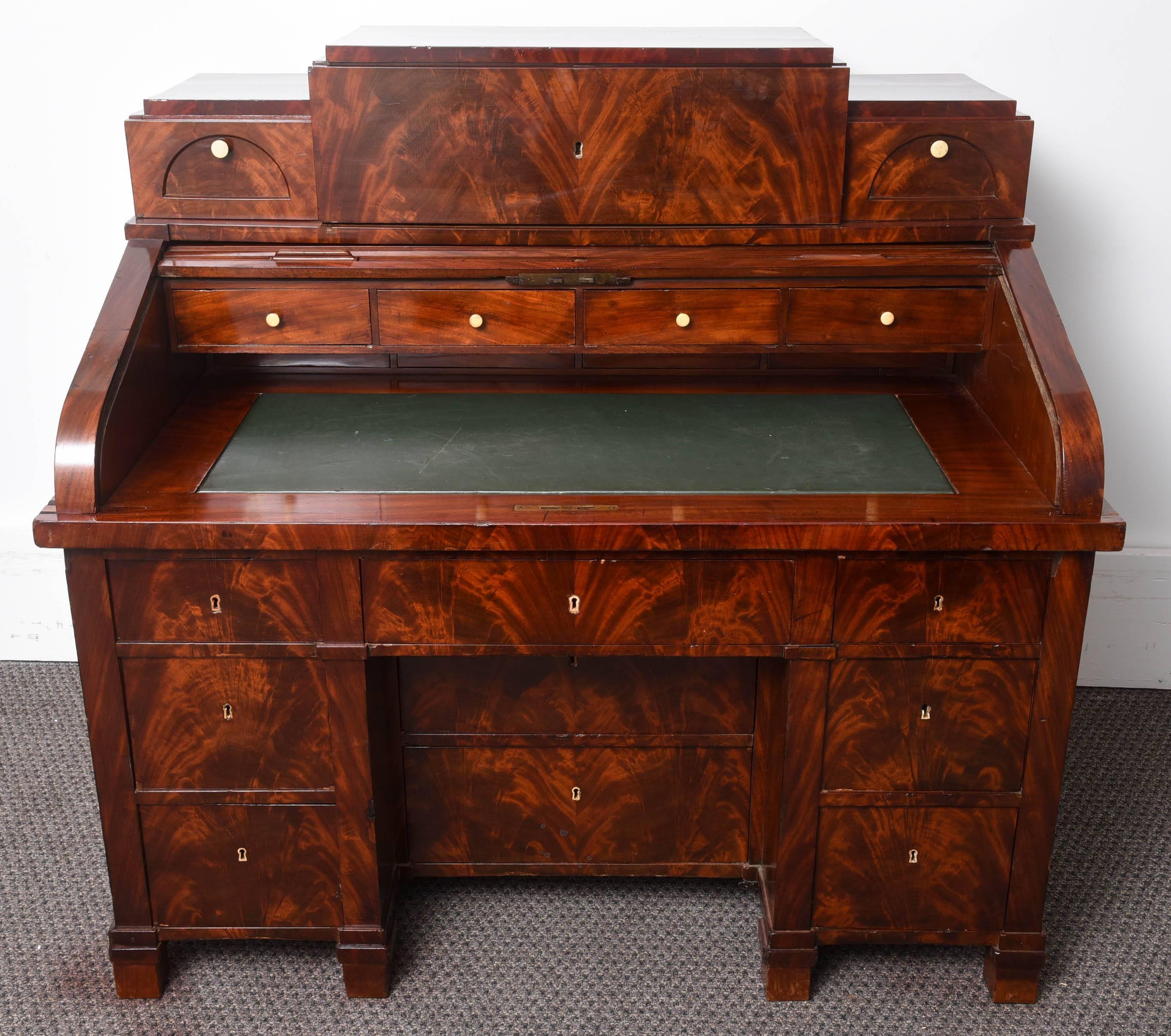 This is a fine example of a 19th century mahogany veneer oversized desk, center drawer flanked by two smaller drawers over roll top, over base, 50