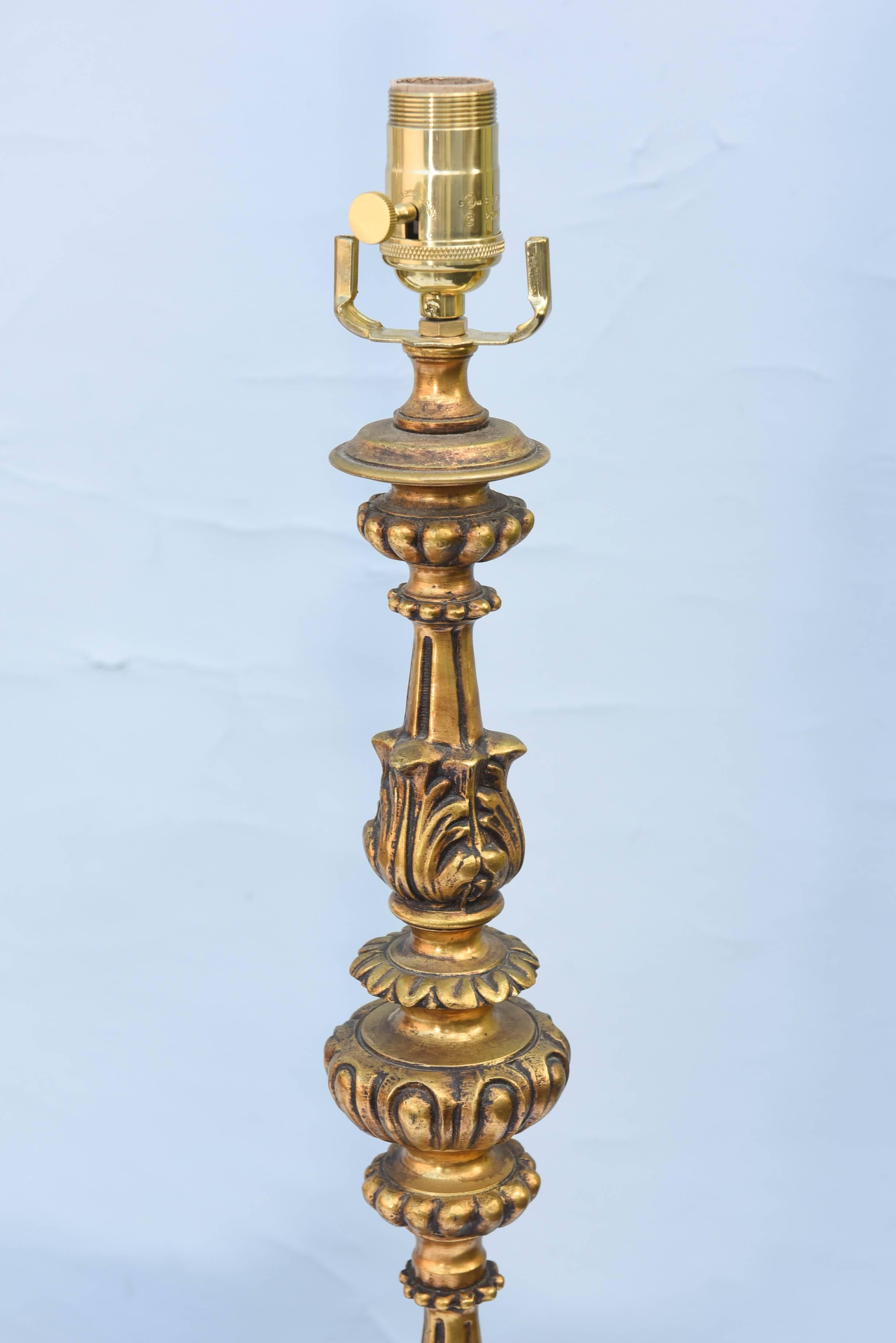 Pair of lamps, of gilt bronze, each formed as turned candlestick with acanthus leaf, gadrooning and beading details, raised on round base with four reclining putto, amid swag and scrolling motifs.