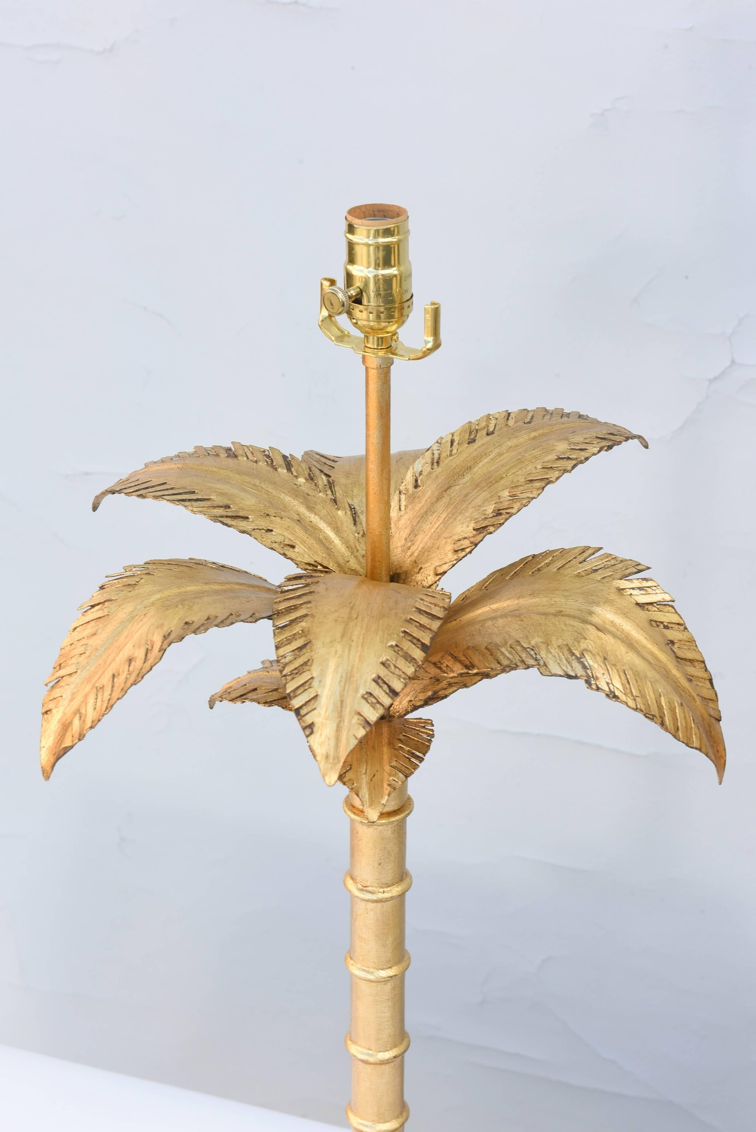 Pair of lamps, of gilded iron, each having well a well-articulated canopy of leaves, over sectioned trunk, on graduated base, set upon round plinth. 

Stock ID: D9270