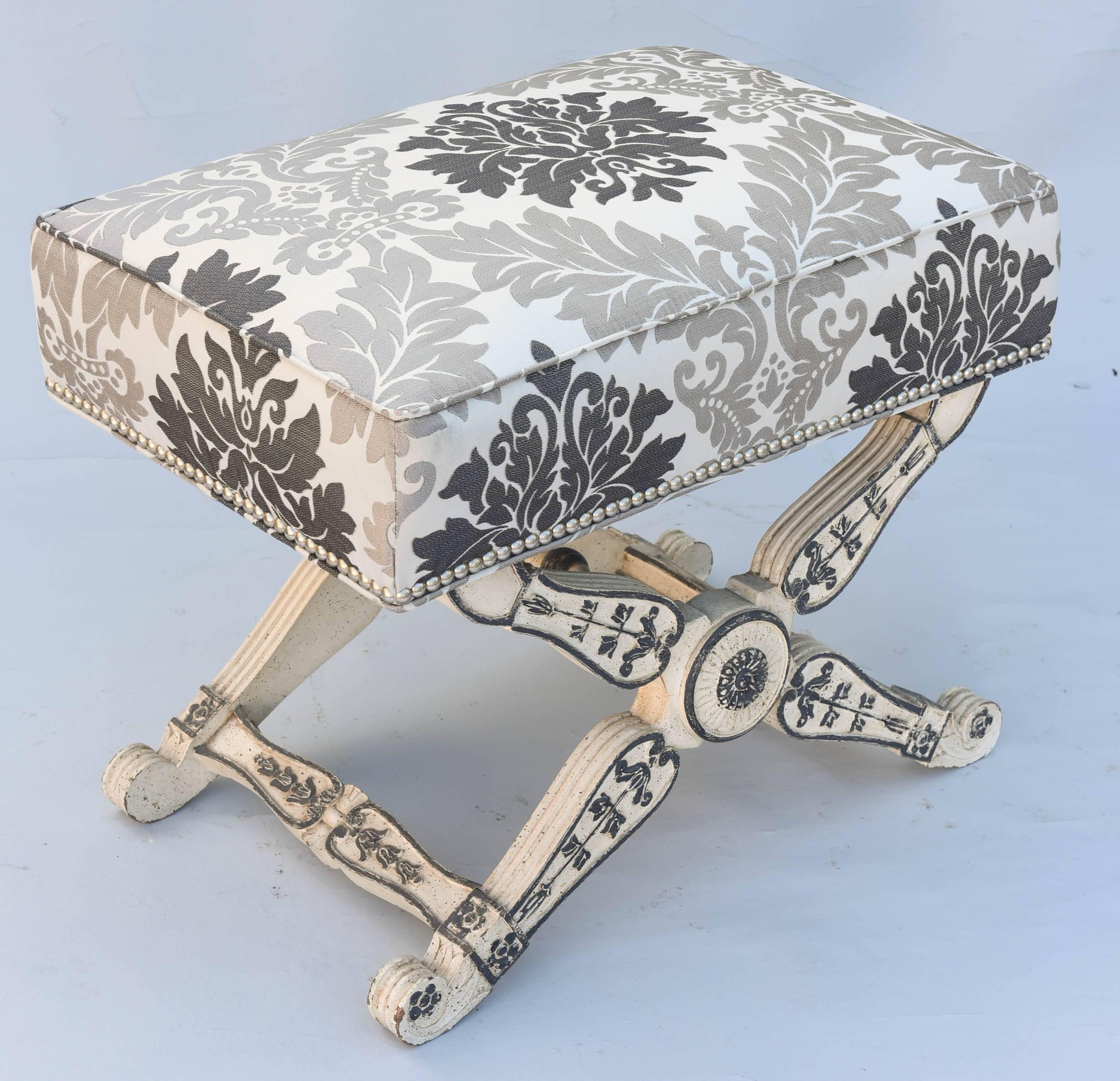 Stool, in Empire taste, having painted frame, upholstered seat with nailheads, raised on x-frame base, its fielded legs outcarved with bellflowers, centered by rosette, three turned stretchers join its legs.

Stock ID: D9250