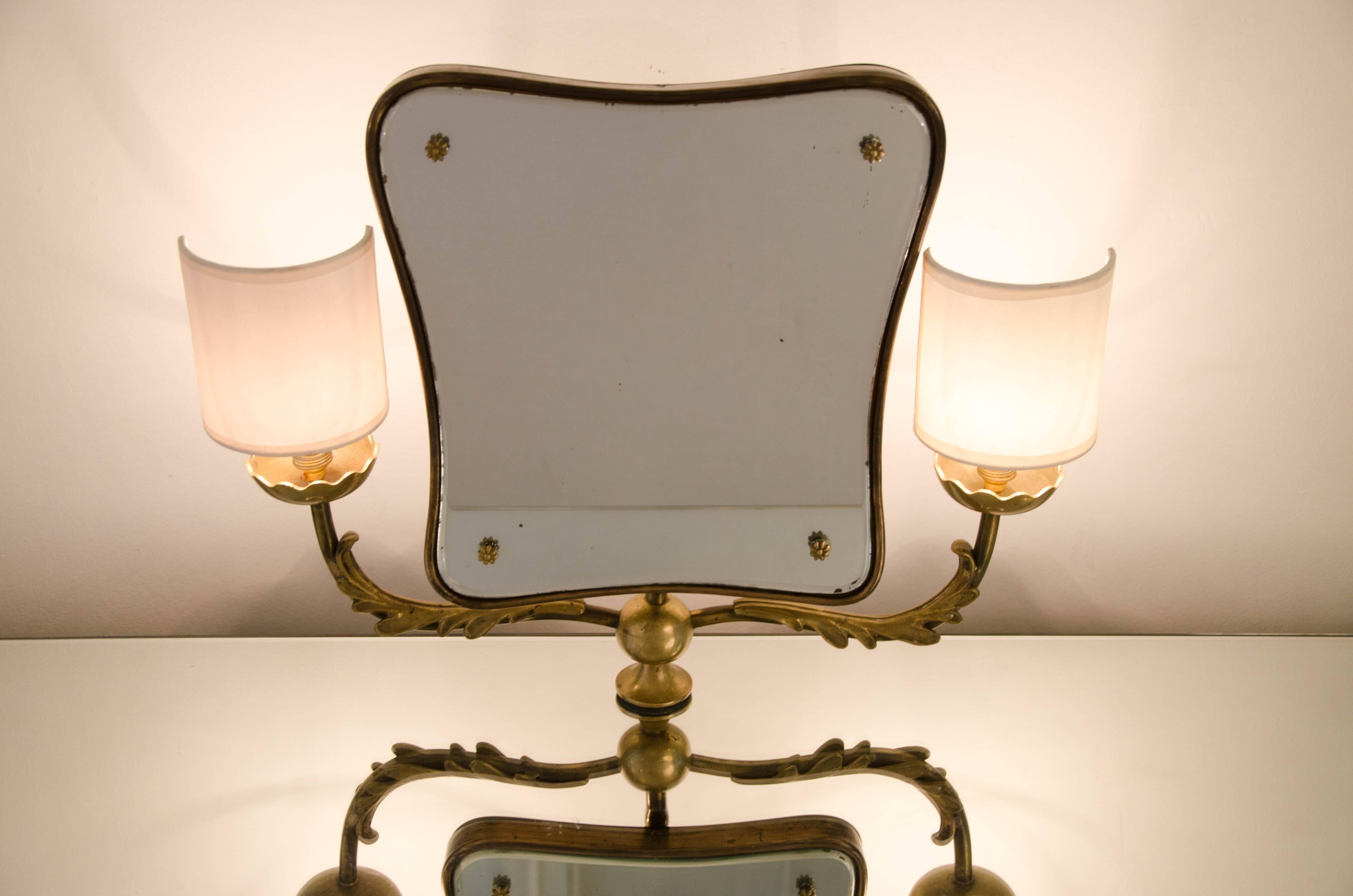 Elegant Italian ebonized dressing table with intricate brass detailing to the legs and feet. Curved tilting mirror with brass trim is supported by a decorative brass arm, which extends to support two side lights. Three curved mirrored drawers