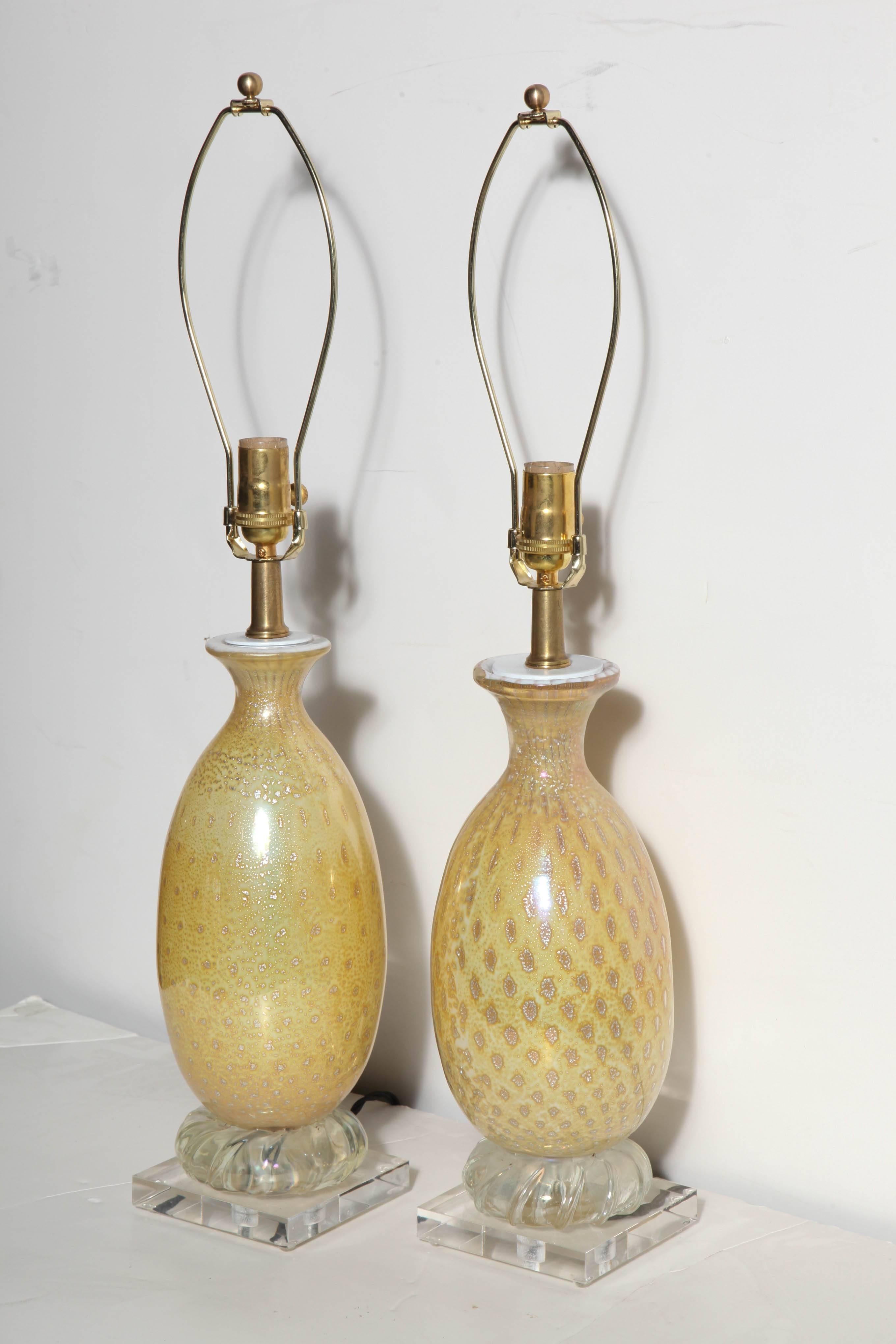 Two Italian Modern Alfredo Barbini style Yellow & White Murano Art Glass Table Lamps. Featuring hand blown bottle forms in White with Silver rimmed Gold inclusions. Brass neck. White cap. With round swirled clear glass detail above square 5H Lucite